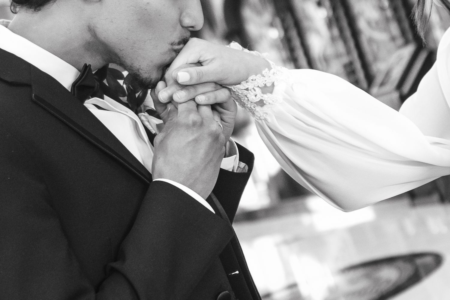 Black and white close-up of hands exchanging wedding rings during a traditional marriage ceremony.