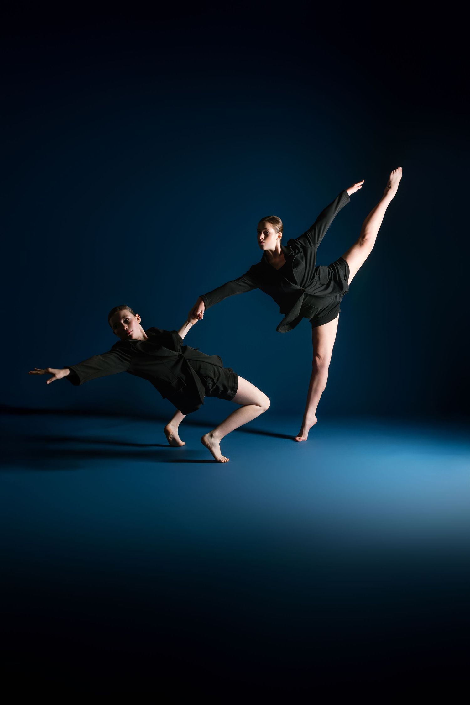 Contemporary dancers perform a dynamic sequence of leaps and movements against a dark blue backdrop.