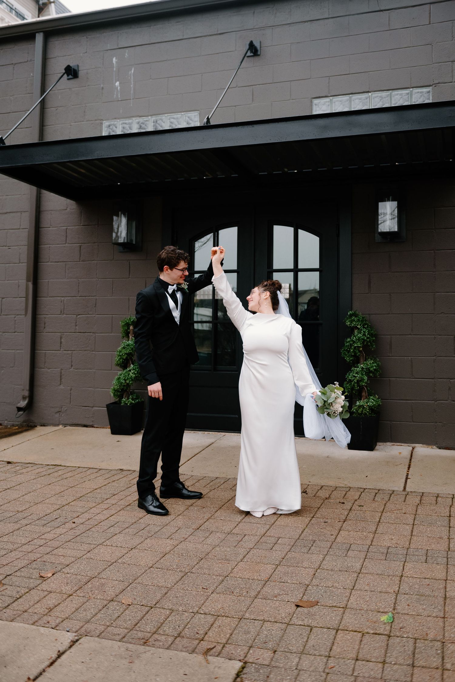 A series of four wedding photos showing a couple dancing and twirling on a brick patio outside a building.