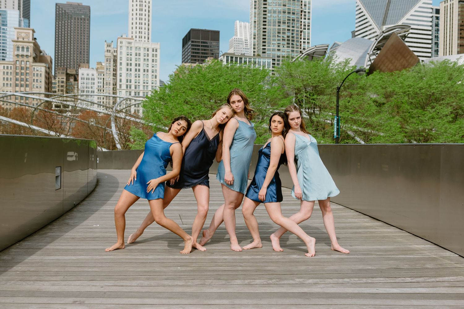 Dancers strike graceful poses on a walkway in Millennium Park Chicago with downtown skyscrapers in the background.