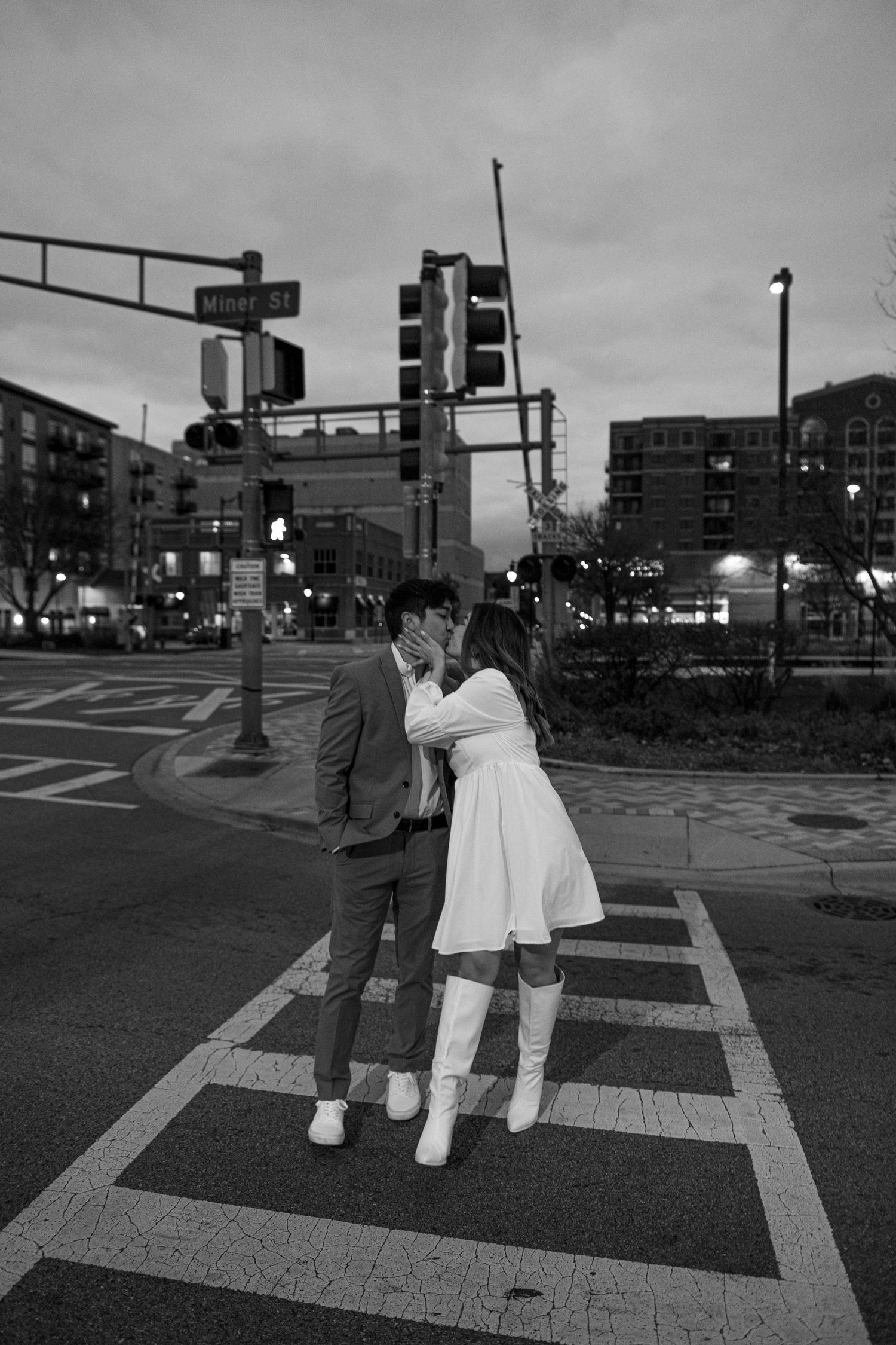 A black and white photo sequence showing two people dancing together on a city street at dusk. Engagement photos