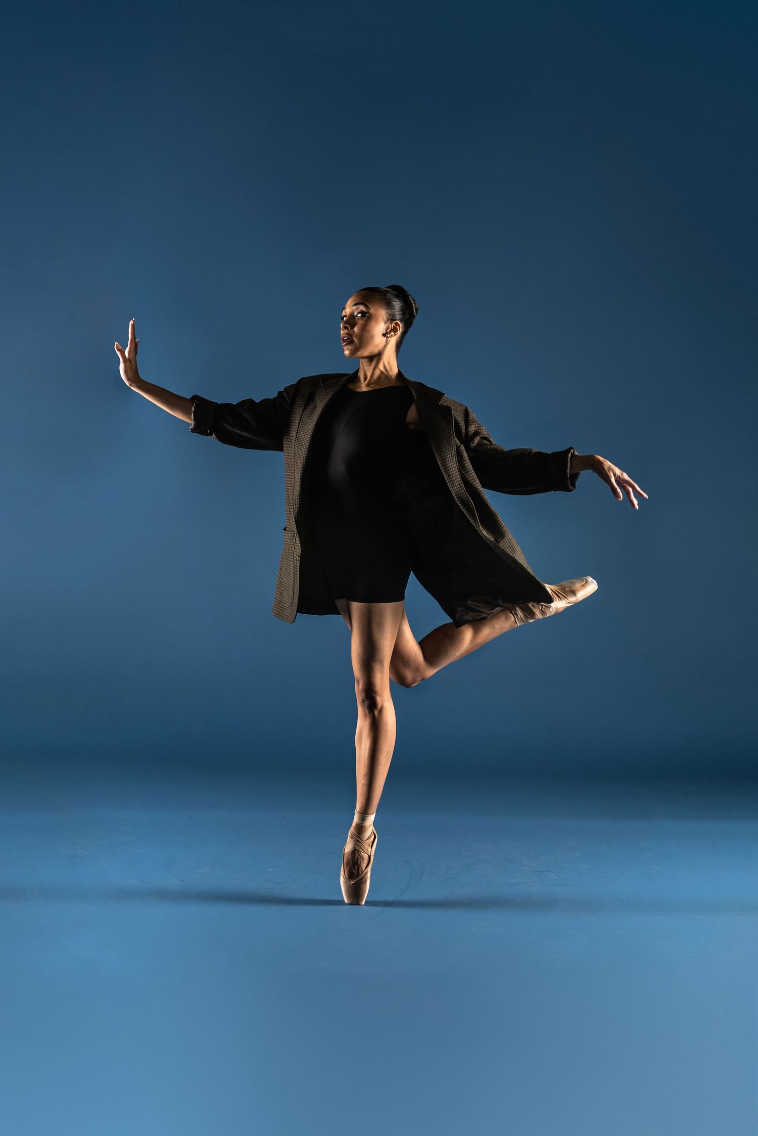 Ballet dancer in black performing graceful movements and poses against deep blue background in fluid motion sequence.
