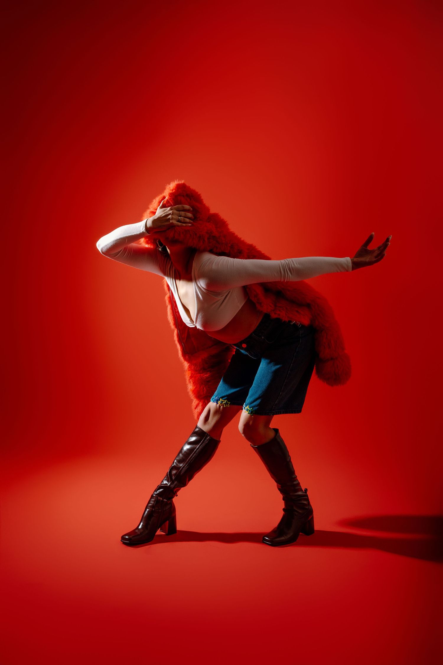Dynamic dancer performs energetic breakdance moves on red background in dramatic lighting and shadows.