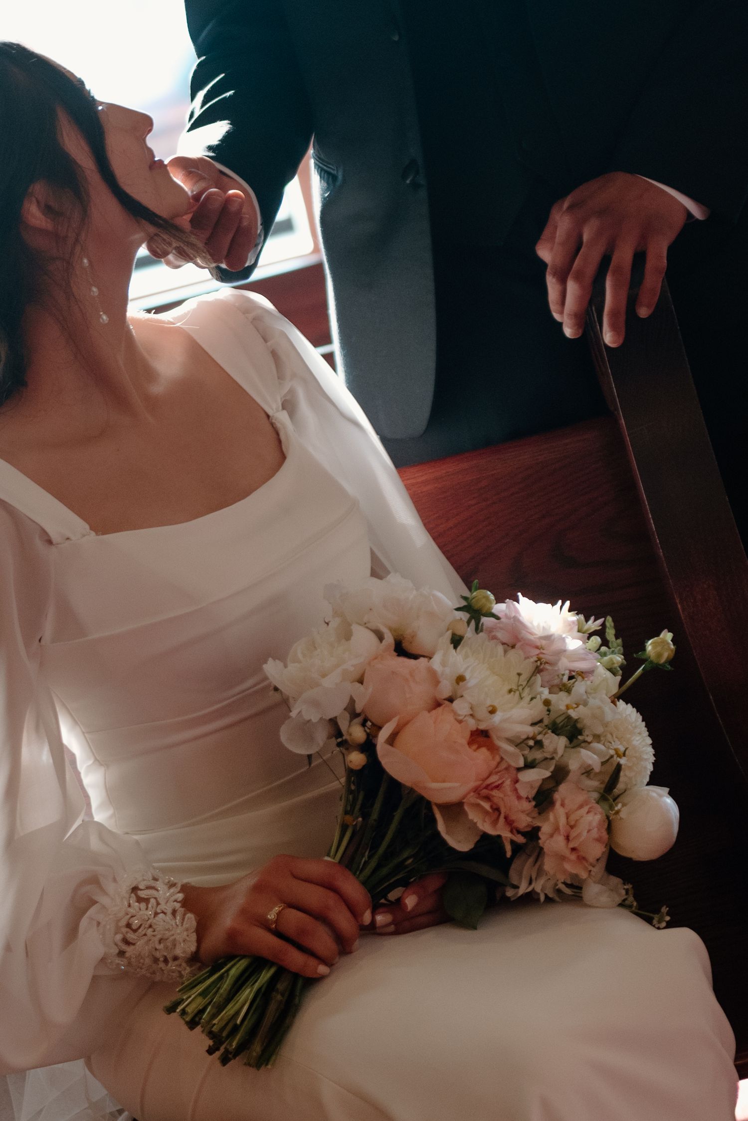 Close-up detail of a white wedding dress with a delicate bouquet of pink and white flowers.