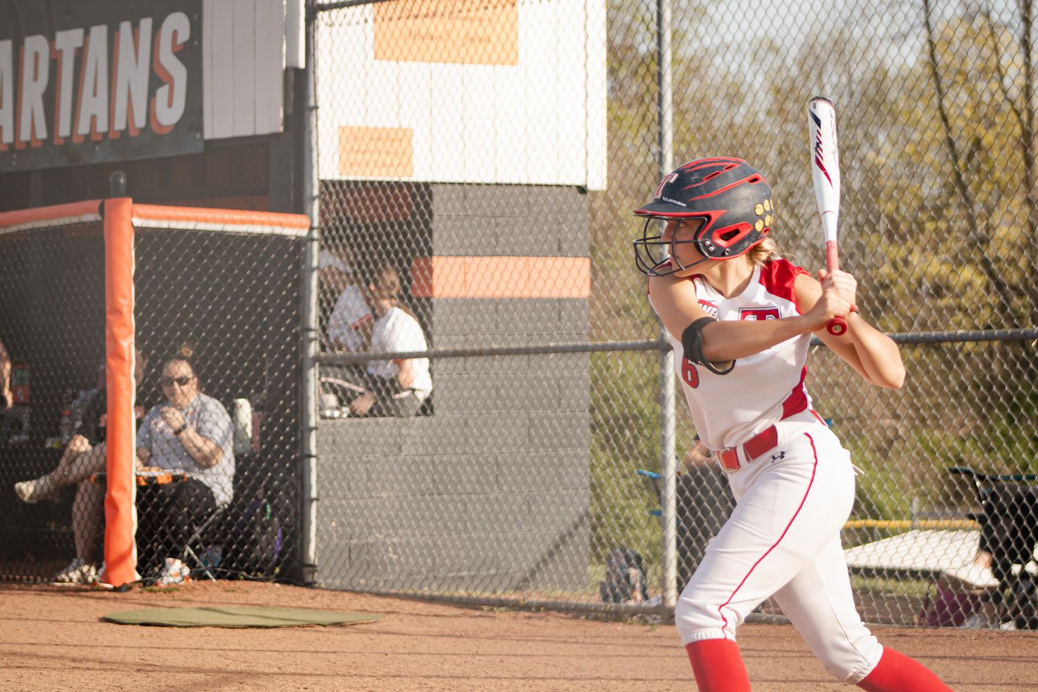 A baseball player in white uniform follows through on their swing during a game.