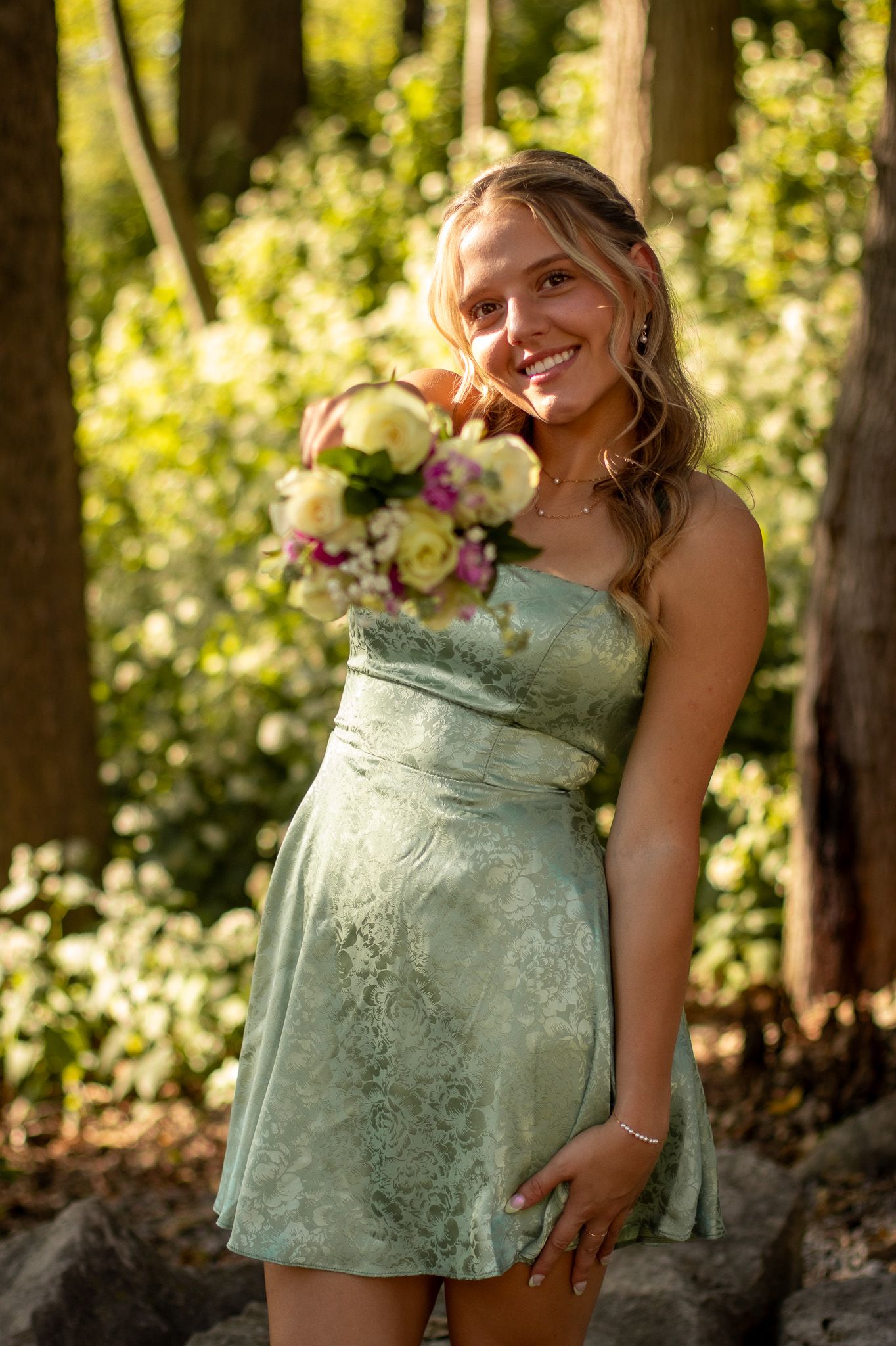 A series of four photos showing someone in a mint green dress posing outdoors in a wooded setting.