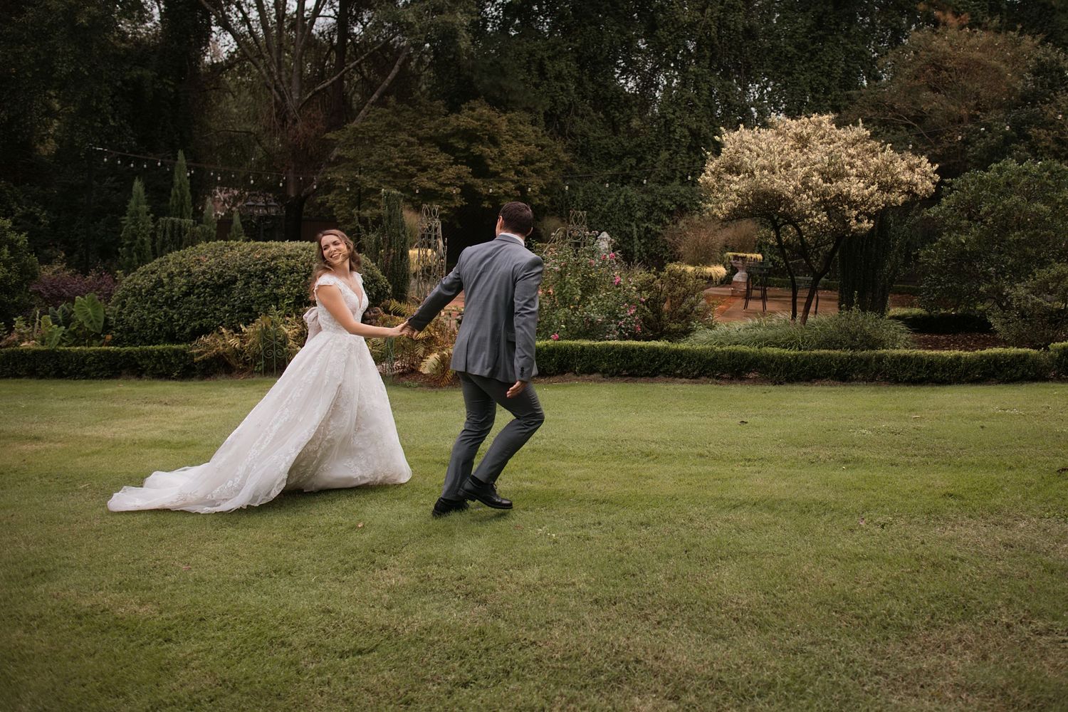 Newlyweds dance together on manicured lawn surrounded by garden scenery. Alex Faye Photography Alex Faye Media Wedding Photographer Raleigh