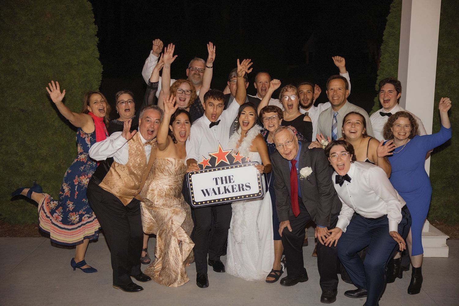 Large wedding party group photo with celebratory poses and 'The Whites' sign. Alex Faye Photography Alex Faye Media Wedding Raleigh
