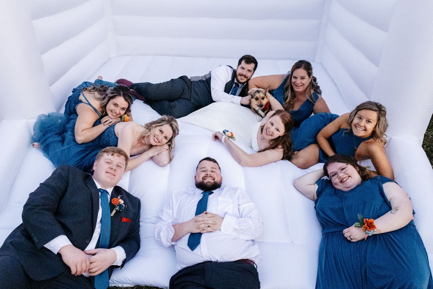 Wedding party lying together in white bounce house wearing navy and white attire. Alex Faye Photography Alex Faye Media Wedding Photographer