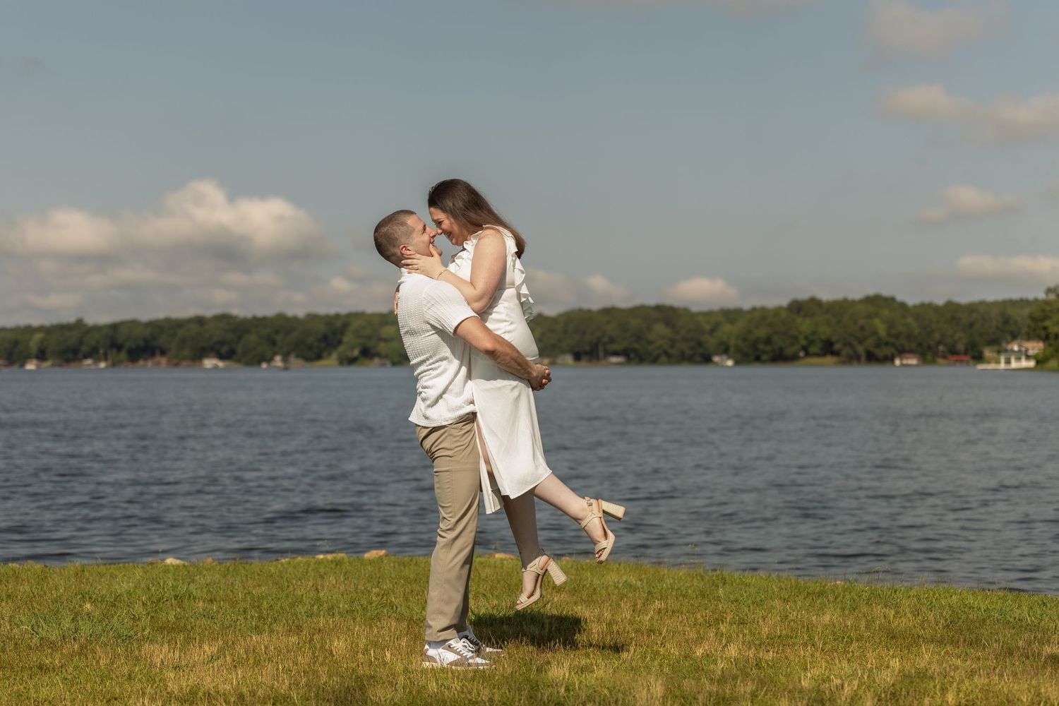 Couple shares a romantic embrace by a lakeside on a sunny afternoon. Alex Faye Photography Alex Faye Media Wedding Photographer Raleigh