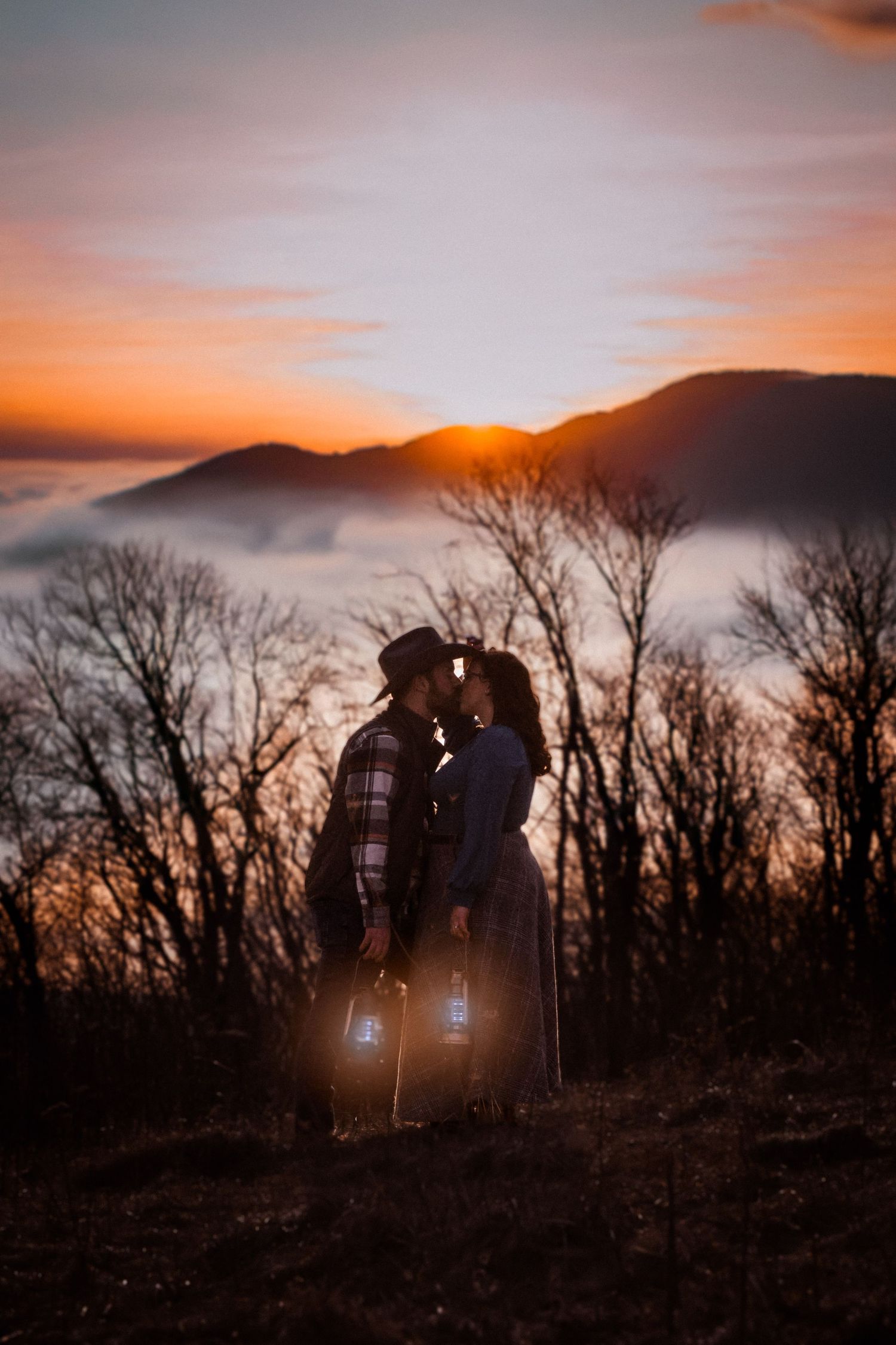 Silhouetted couple shares romantic moment at sunset against mountain backdrop with dramatic sunset Alex Faye Photography Alex Faye Media