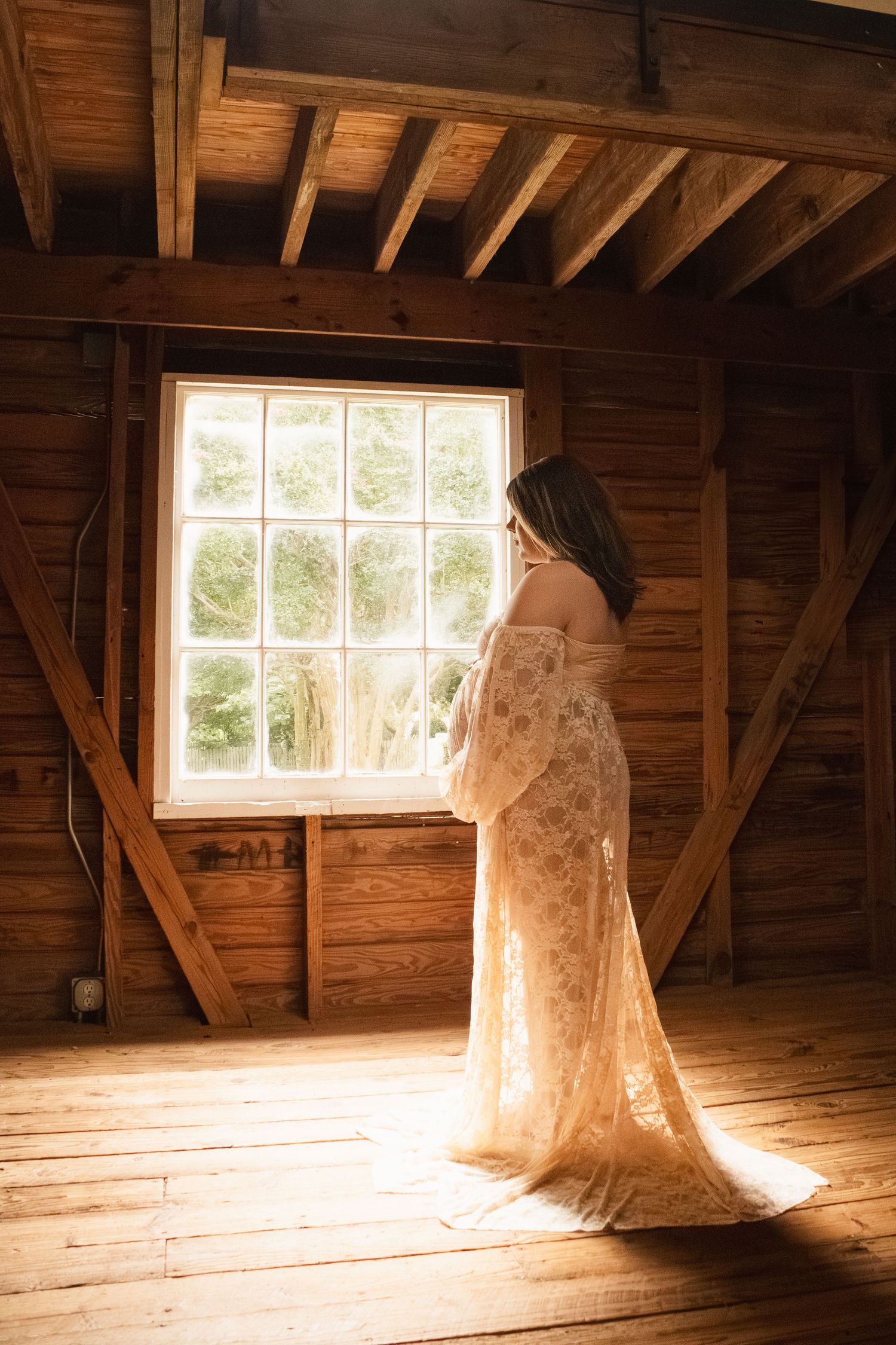 Sunlight streams through window illuminating figure in vintage lace gown in rustic wooden barn. Alex Faye Photography Alex Faye Media