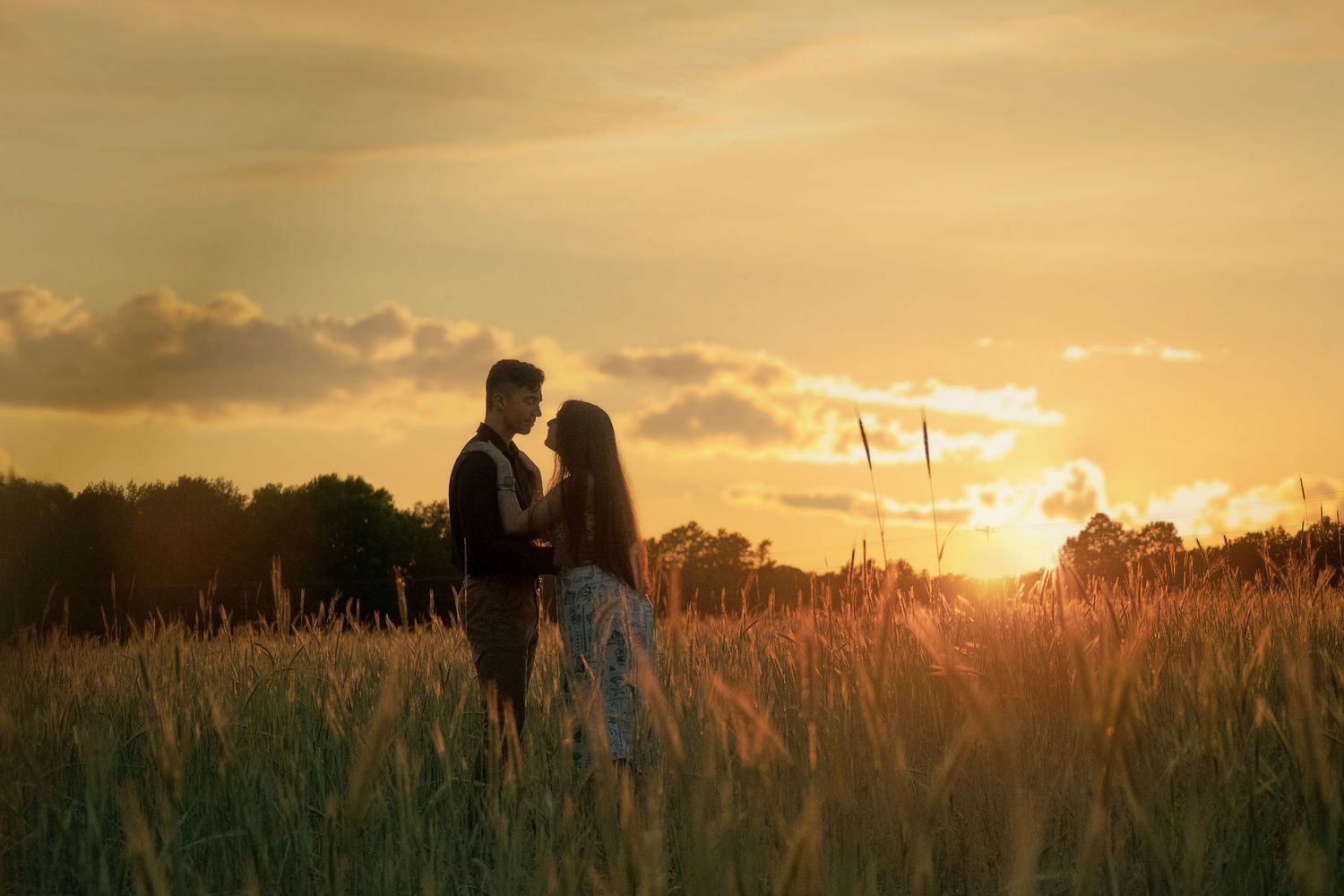 Silhouettes of couple against dramatic golden sunset in wheat field. Alex Faye Photography Alex Faye Media Wedding Photographer Raleigh