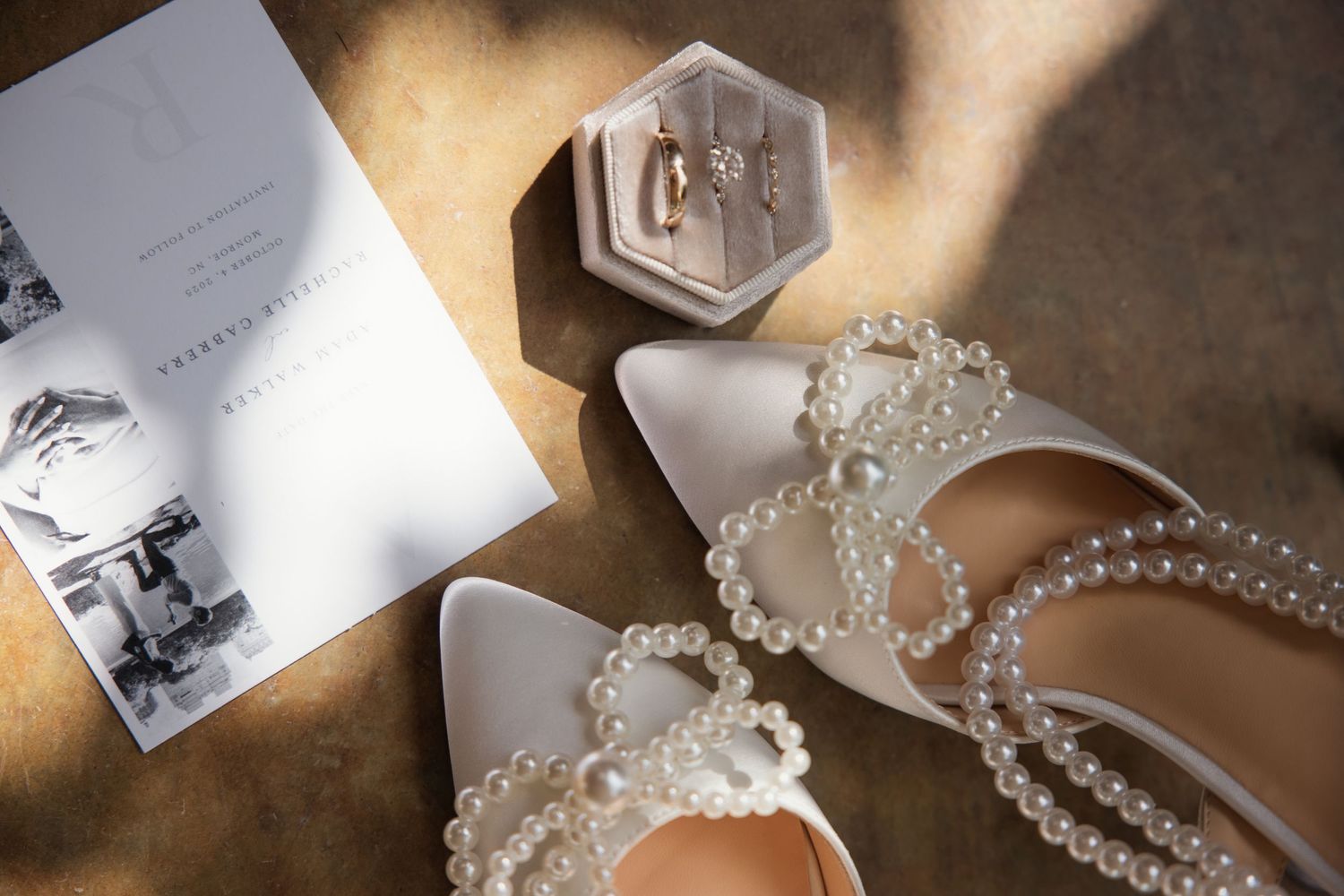 Wedding accessories including pearl necklace, white shoes and photos arranged on textured surface. Alex Faye Photography Alex Faye Media