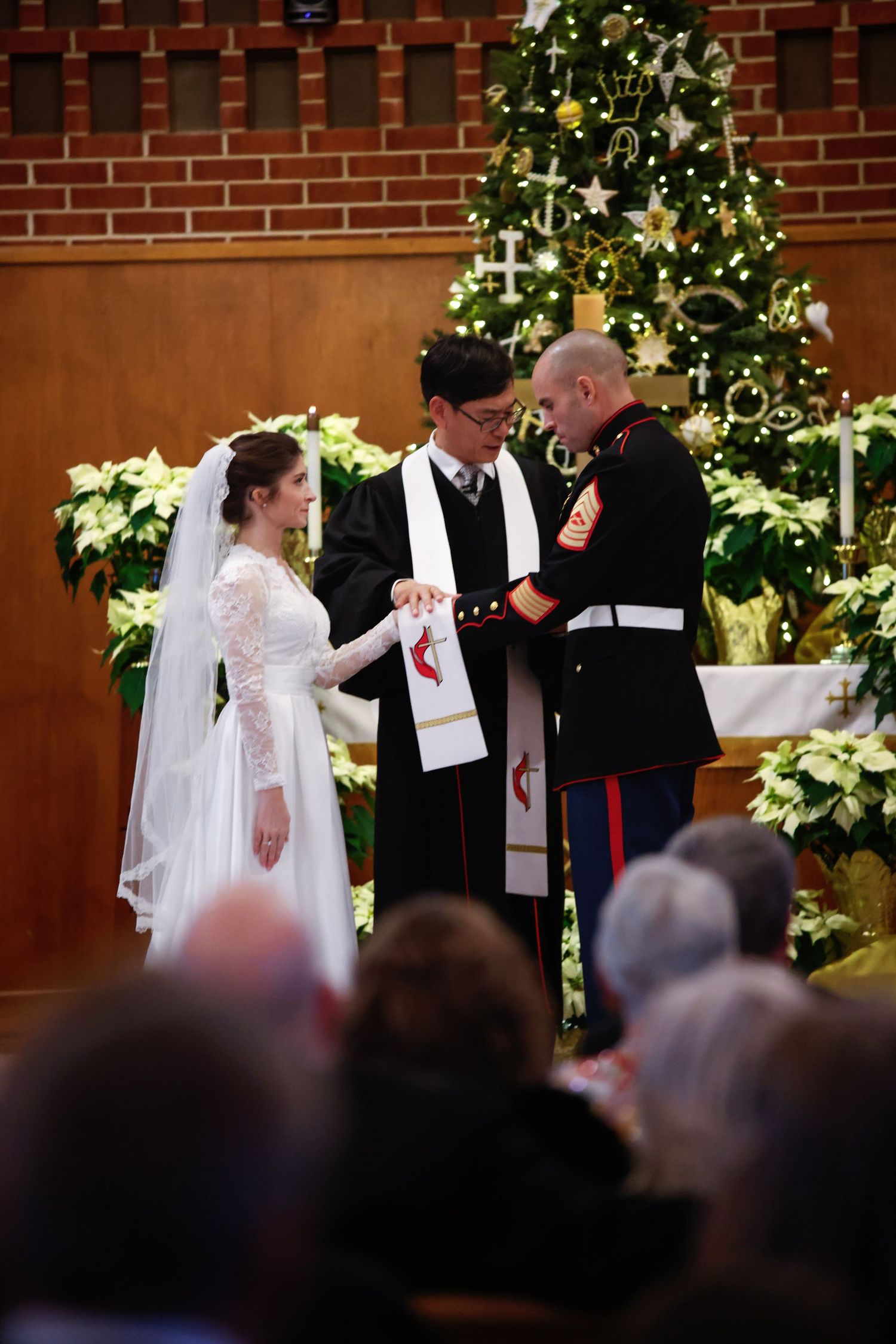 Military groom and bride exchange vows with officiant at Christmas wedding ceremony in church.