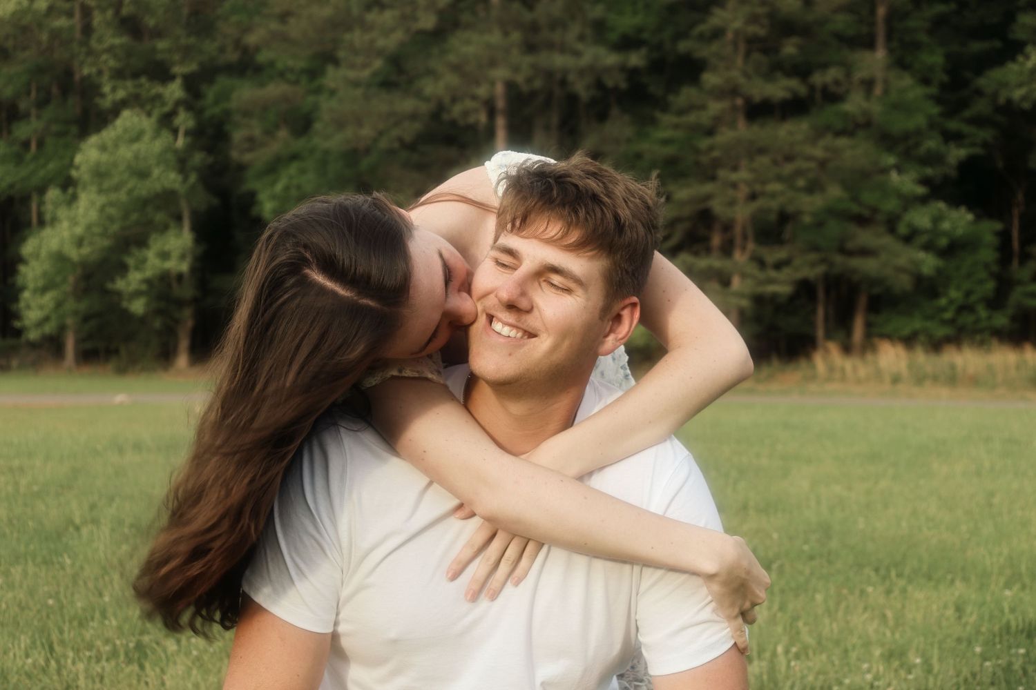 Couple shares playful moment while embracing in green field. Alex Faye Photography Alex Faye Media Wedding Photographer Raleigh