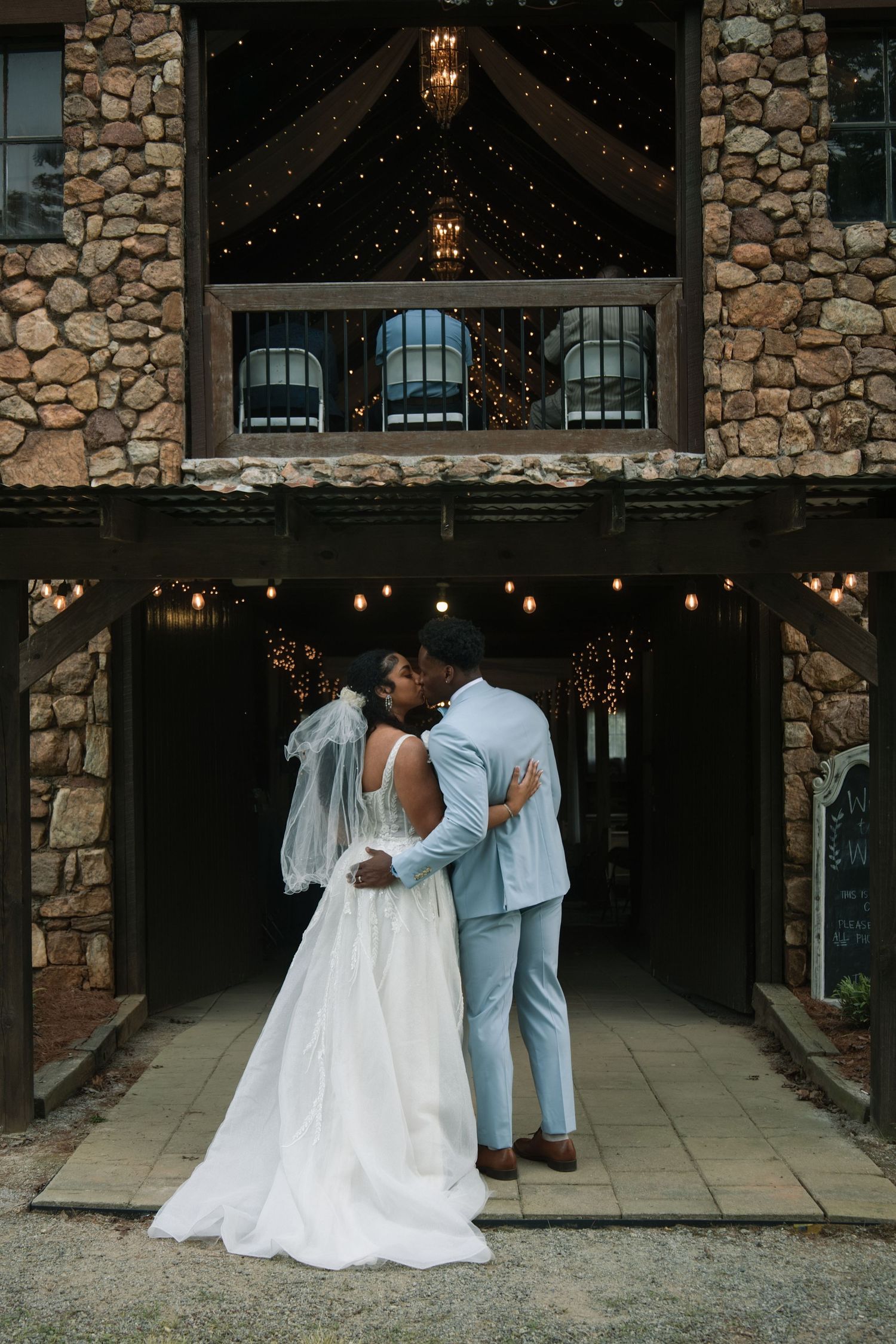 Newlyweds sharing romantic moments against a rustic stone wall backdrop. Alex Faye Photography Alex Faye Media Wedding Photographer Raleigh