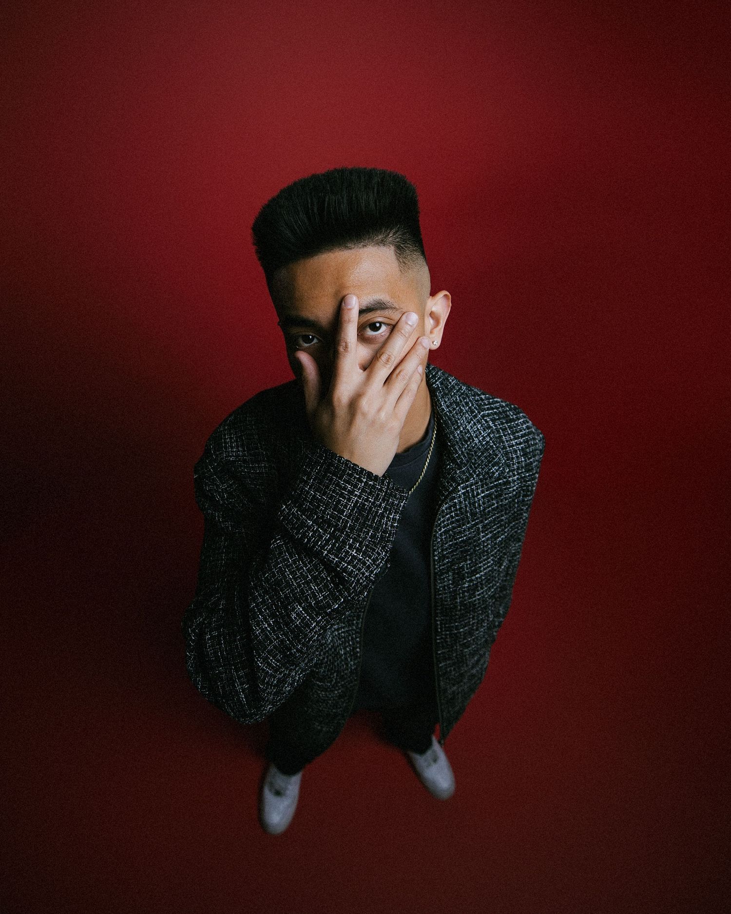 Person in dark sweater covering face with hand against deep red background showing progression of emotional distress.