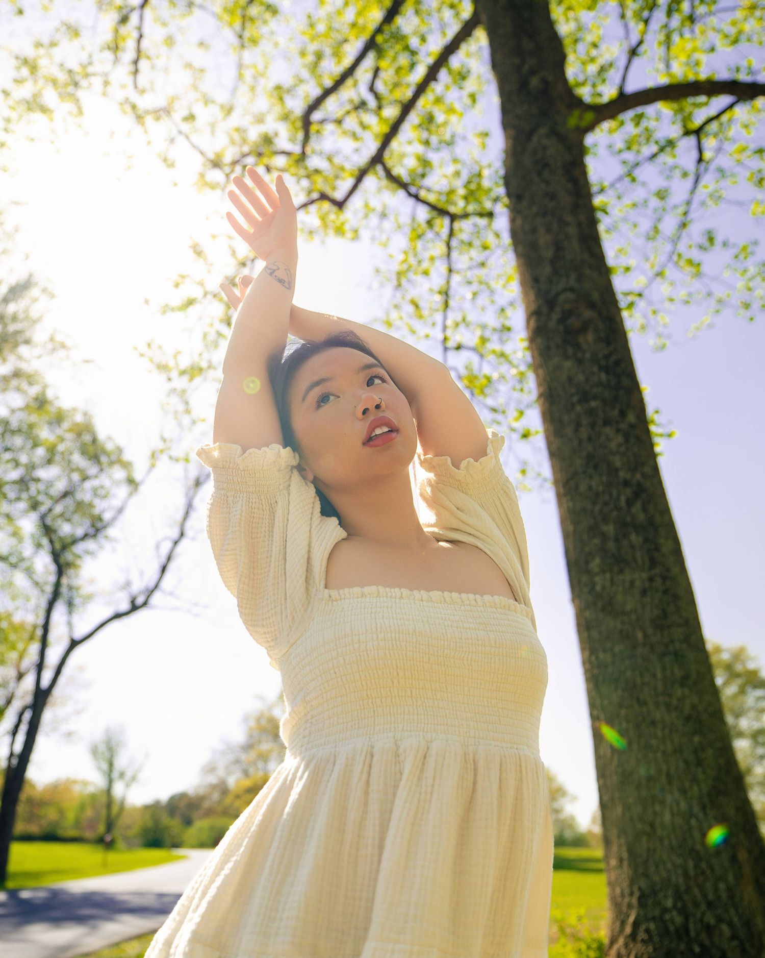 Wide-angle professional photoshoot of a model in a bright, grassy park setting