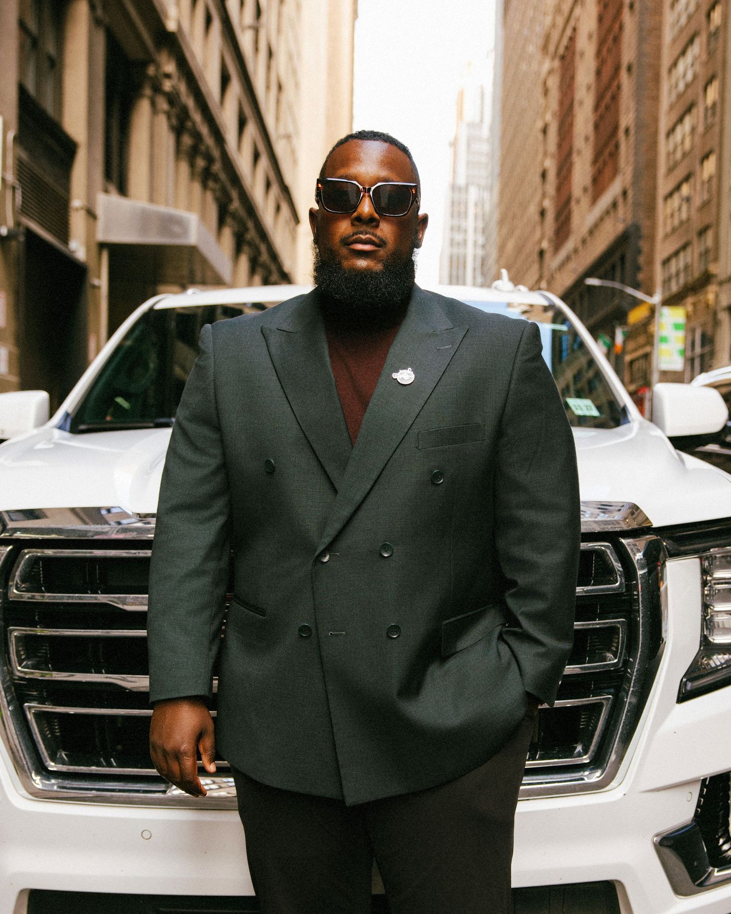 Ross, owner of a private car service in NYC, posing in a suit in front of his fleet of vehicles during a brand photoshoot