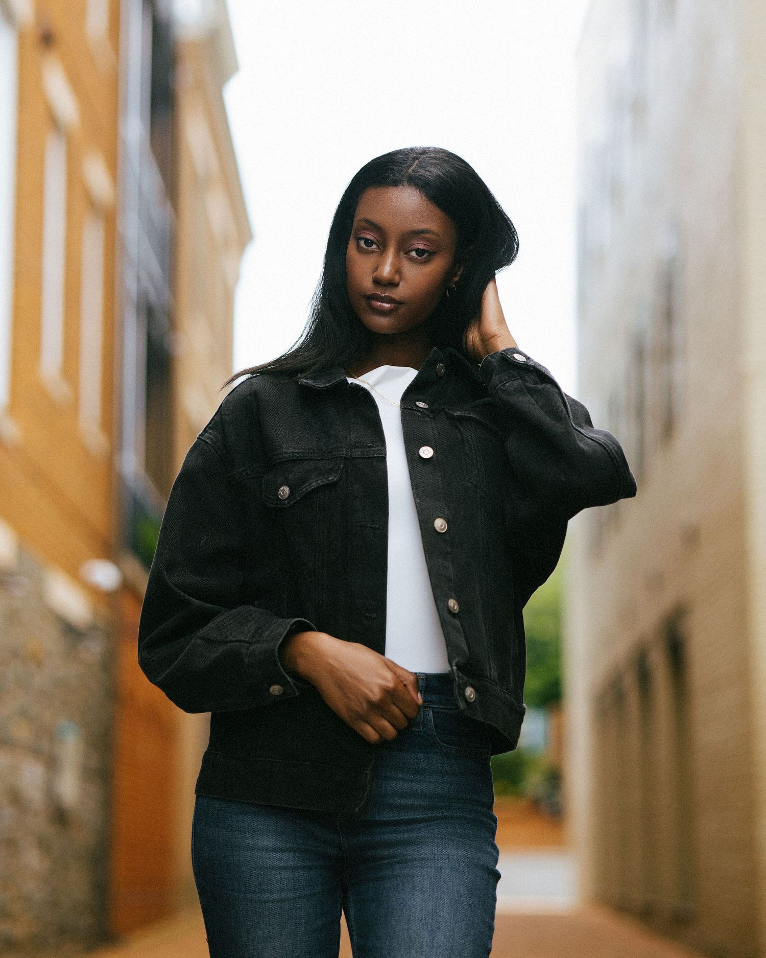 A model in a black jacket and jeans poses casually against a light-colored wall in a split photo collage.