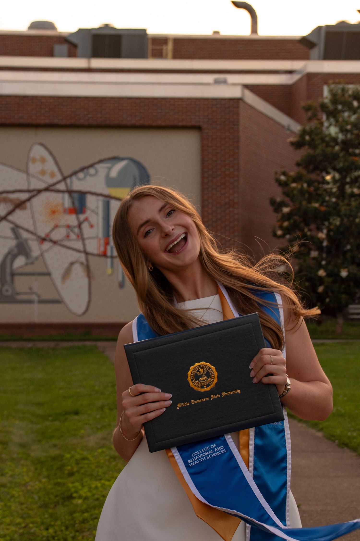Graduate smiling while holding their diploma