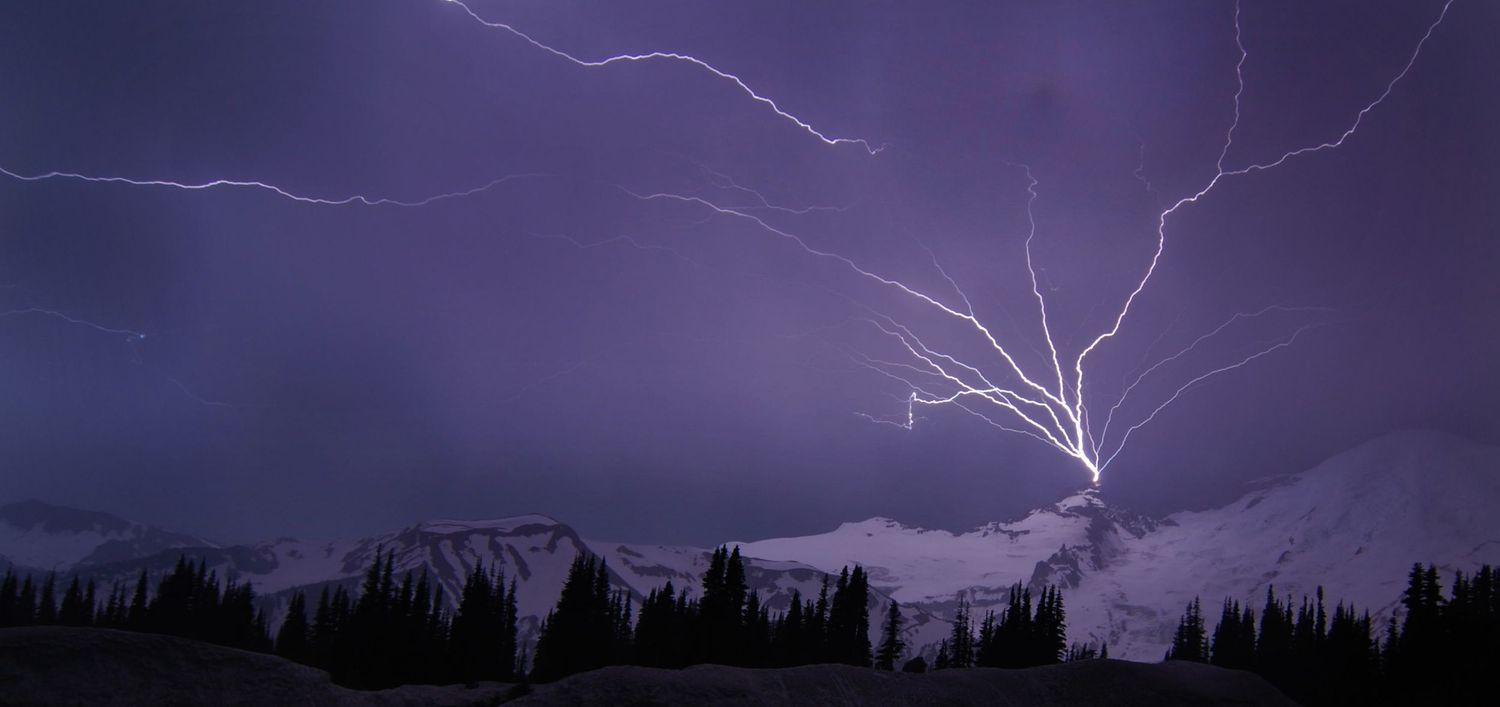 A long exposure capture of a dramatic fork of lightning that fanned across above the summit of Little Tahoma, captured from the Day Lodge.