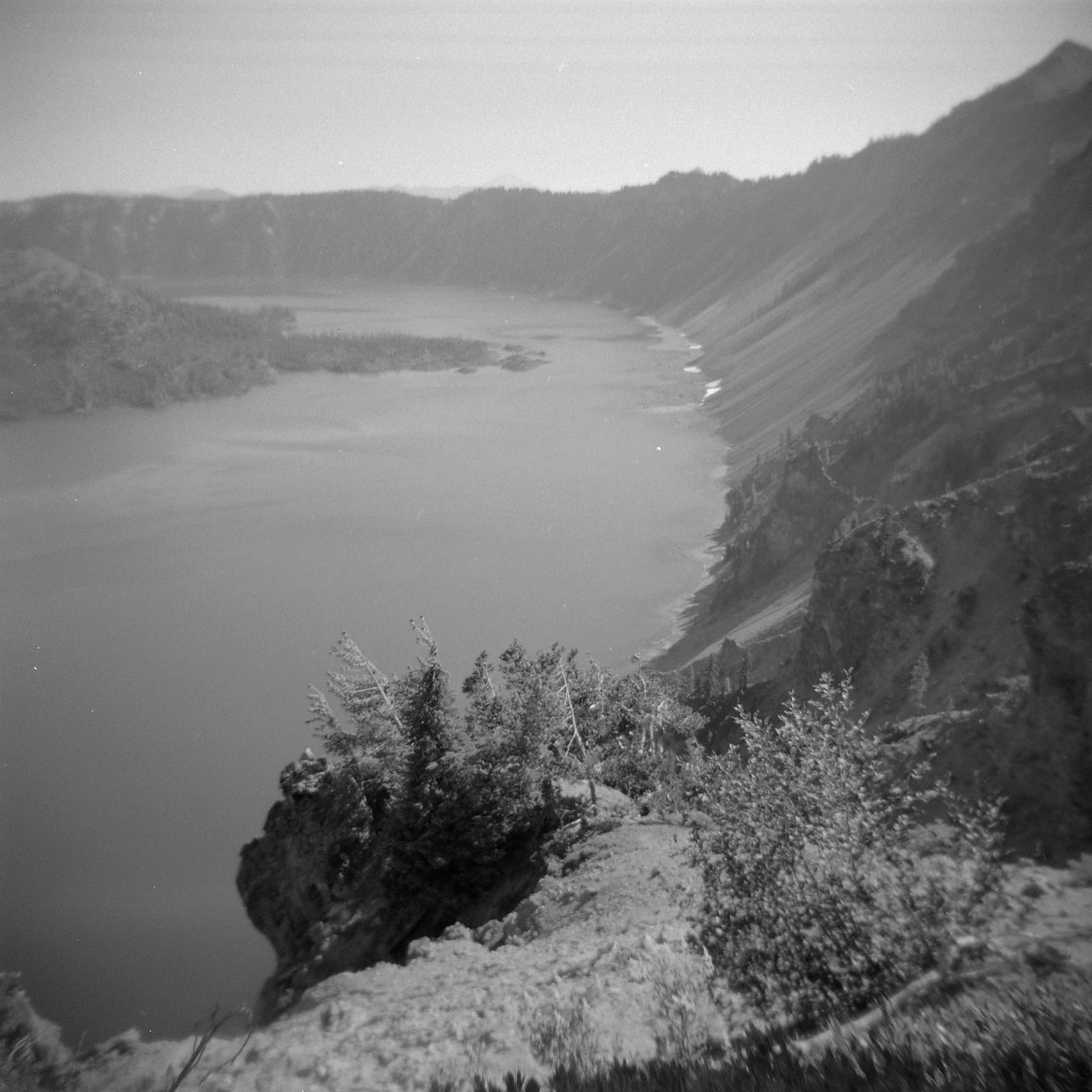 A black and white film Holga photograph of the rim of Crater Lake in Oregon.
