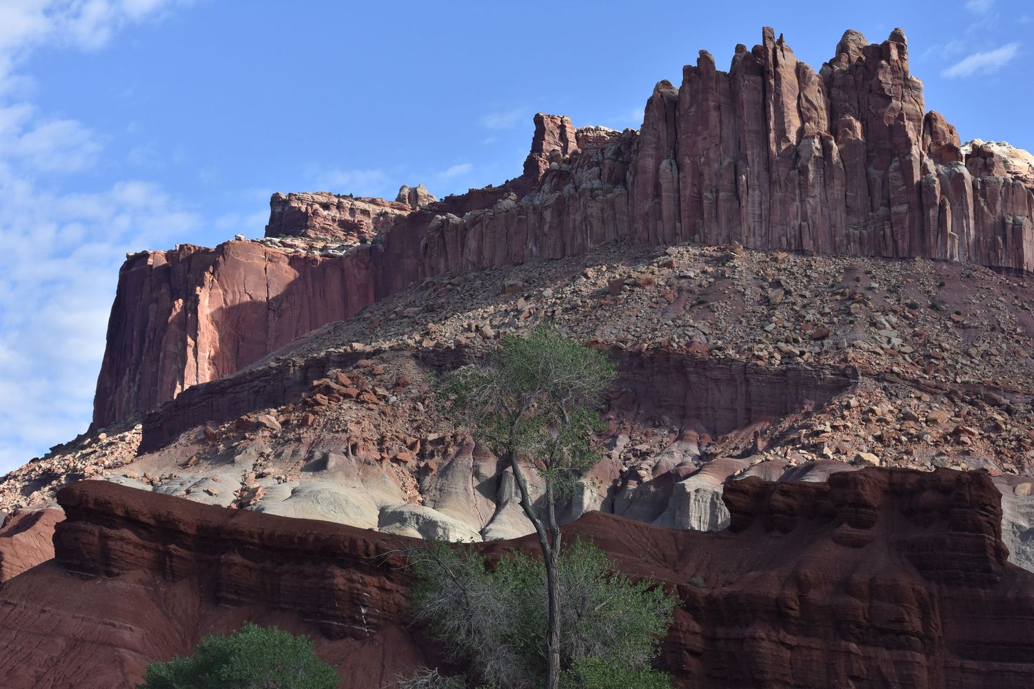 Sandstone cliffs with different rock units eroded differently alongside a highway in the southwest of the US on a clear day.