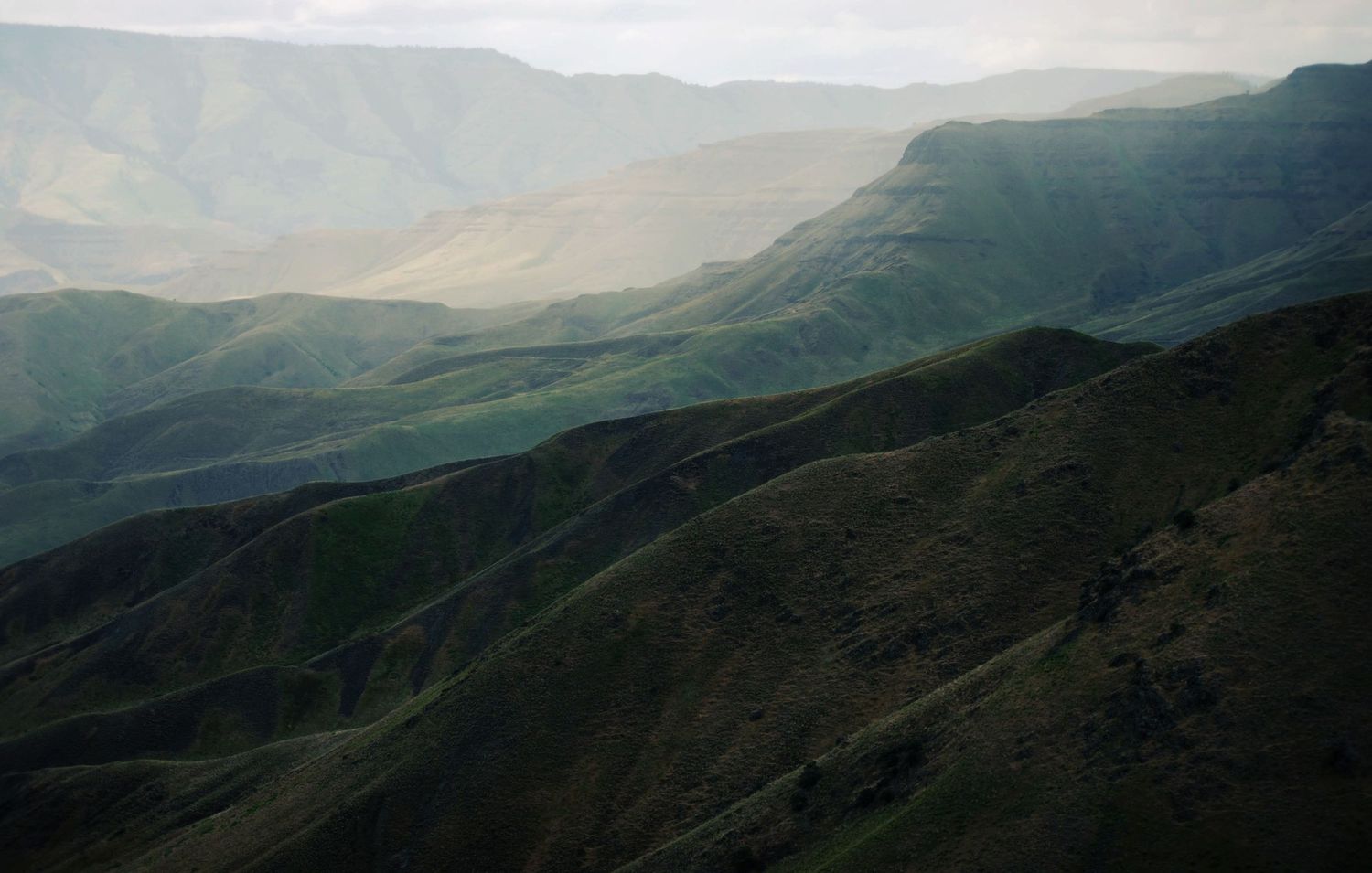 A softly lit photo of layers of sedimentary erosional hills along the Snake river.