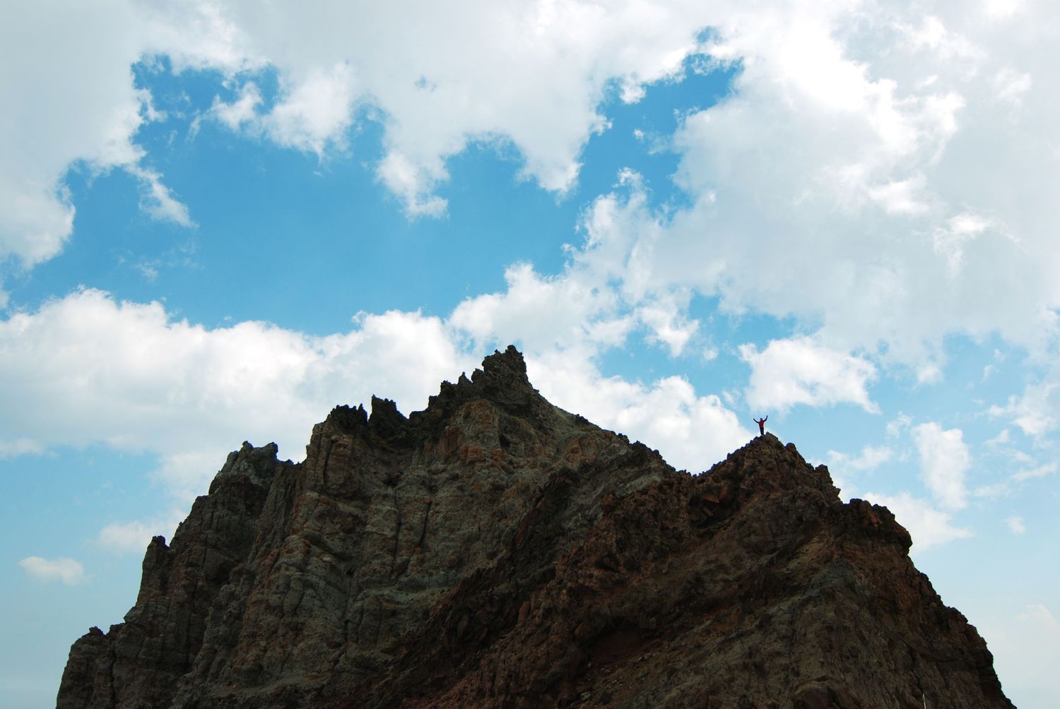 Steamboat Prow is a cliff that rises above Camp Schurman and here hosts a tiny figure raising their arms in celebration against the sky.