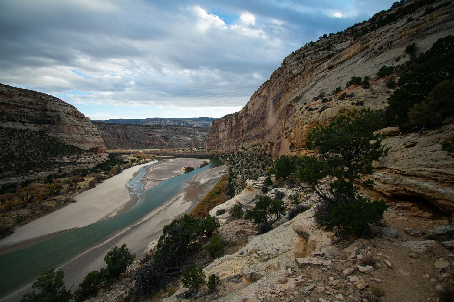 The untamed Yampa river cuts through a big sandstone valley seem from along a cliffside trail in Dinosaur National Monument.