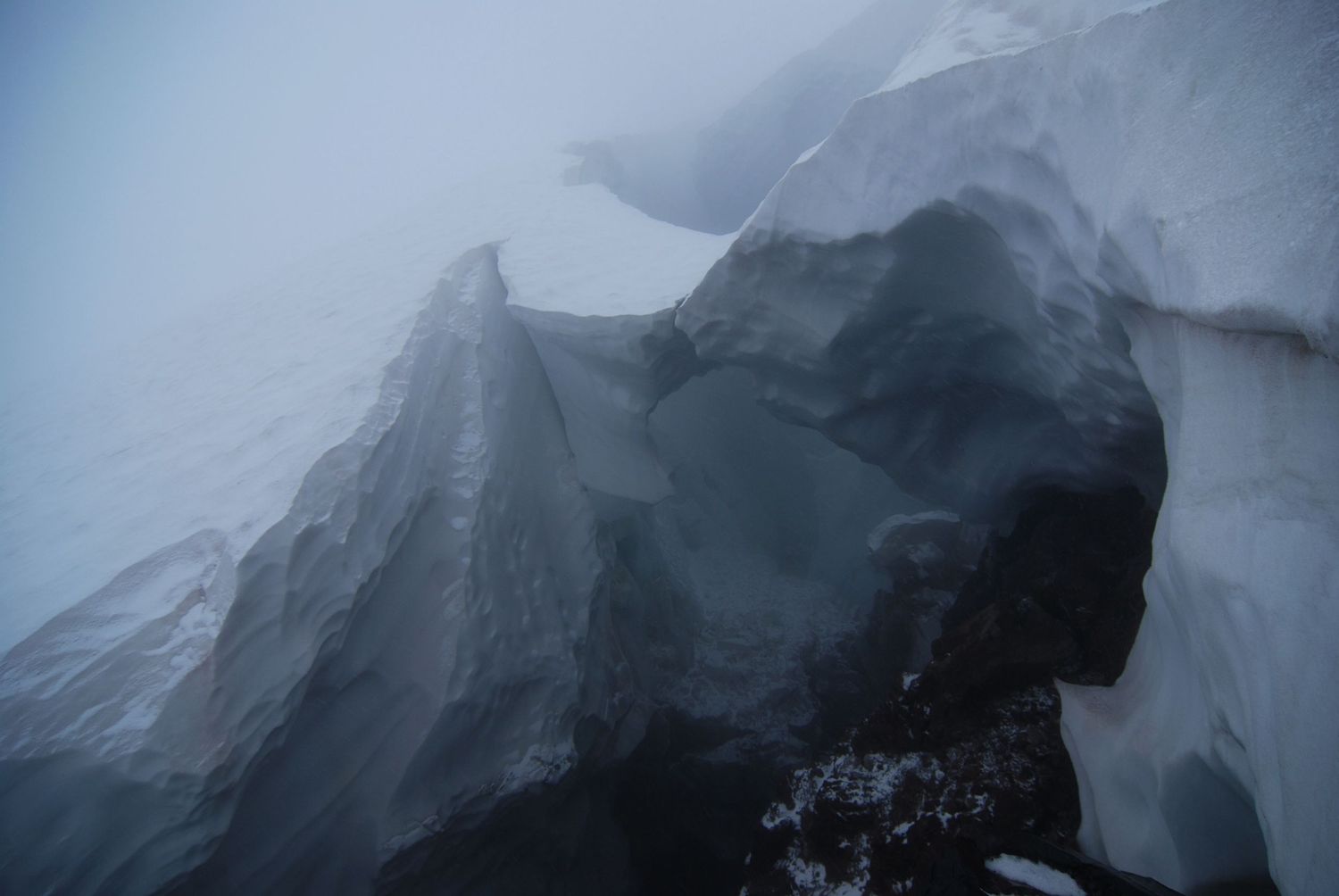 A foggy late day view of a snow bridge near Camp Schurman on Mount Rainier, one of the high camps for climbing the mountain.