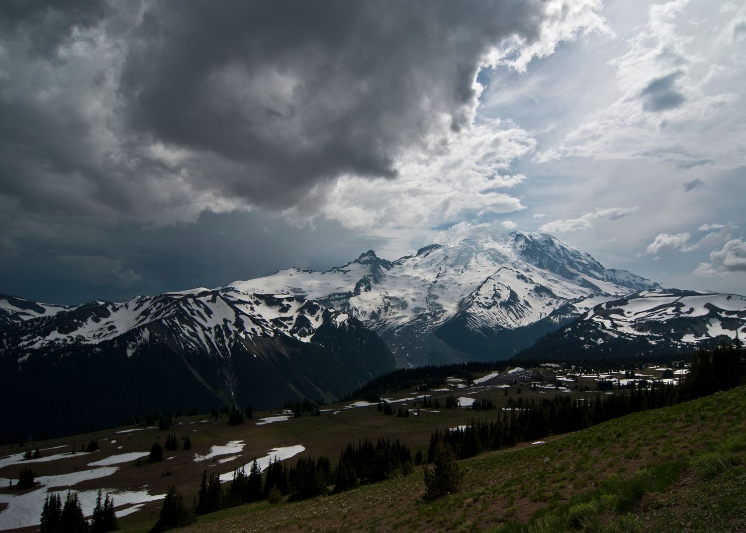 A moody cloudy day at Mount Rainier, the mountain is seen from high on Sourdough Ridge near Sunrise, with sub-alpine fields below.