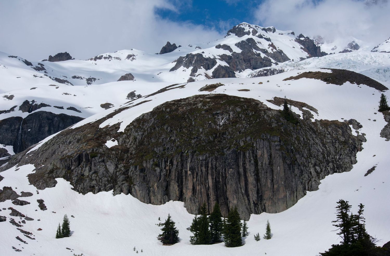 A snowy early spring view of a beautiful cliff near Emerald Ridge on the side of Tahoma, a large mountain.