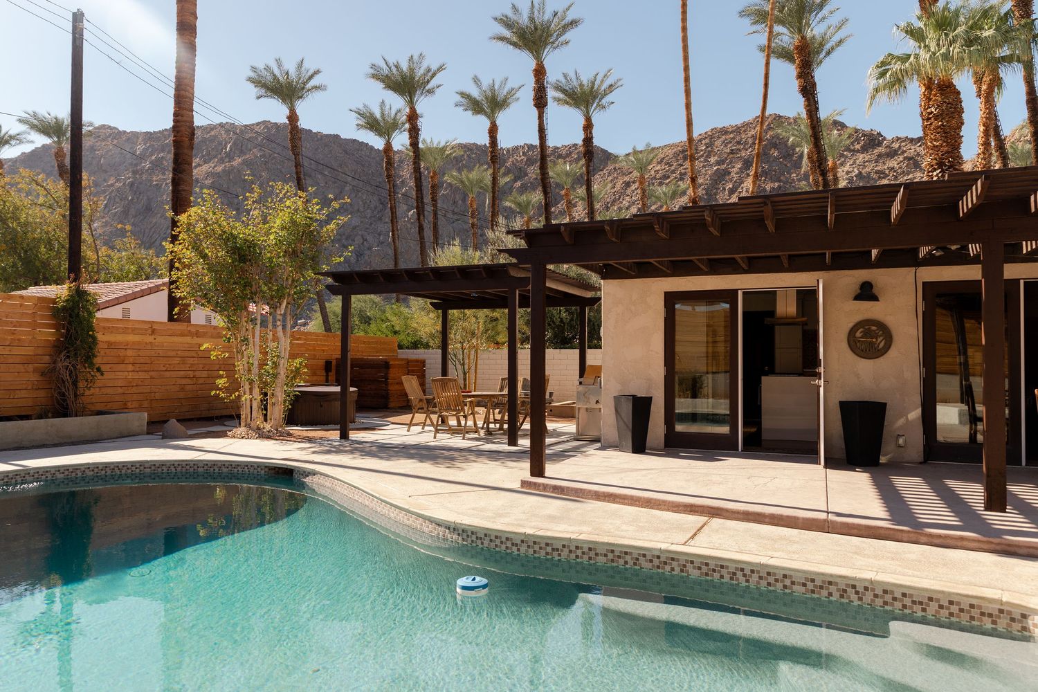 Desert home pool with pergola patio, palm trees, and mountain backdrop in Palm Springs.
