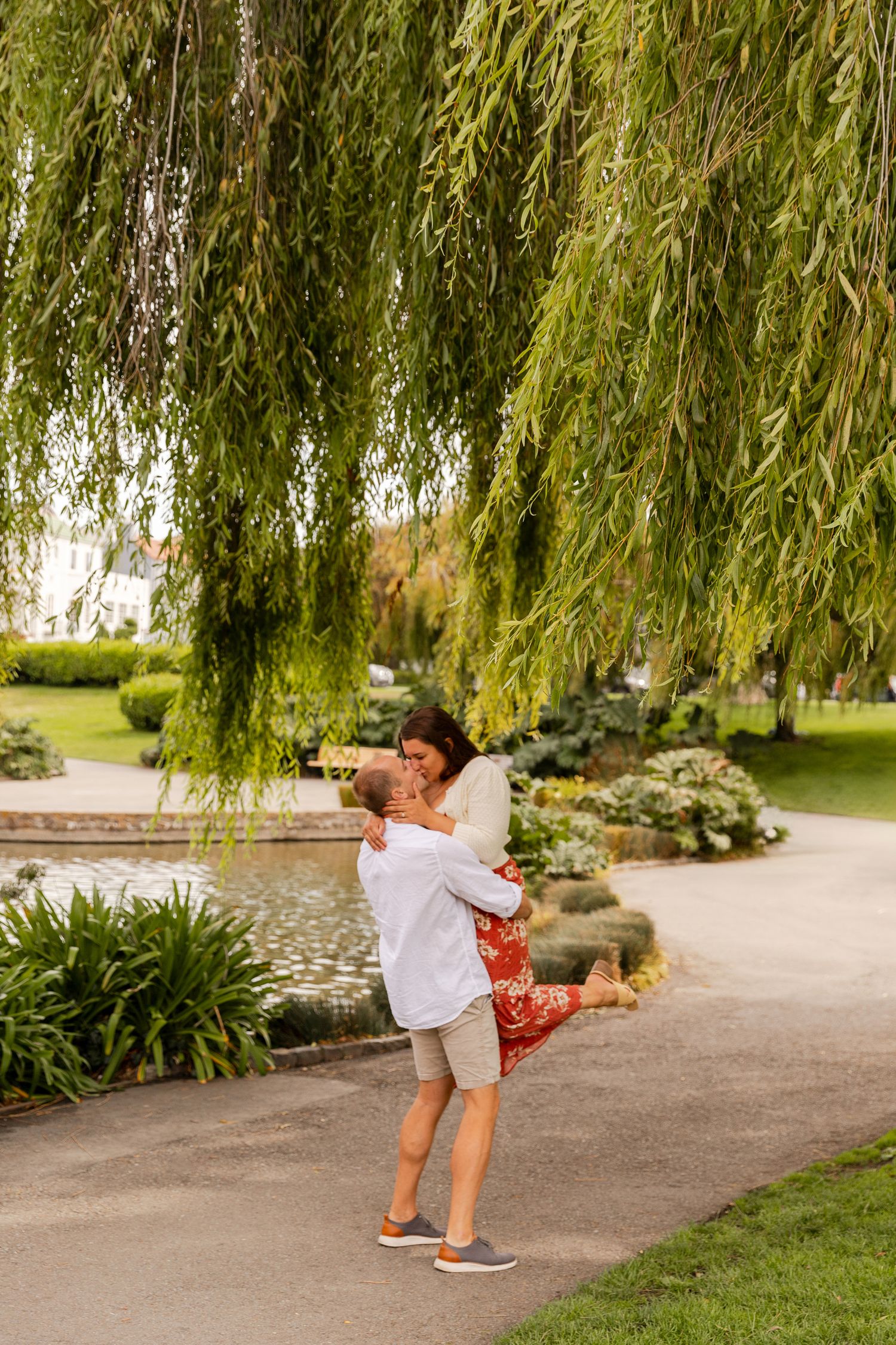 A sequence of four photos showing a person in white spinning around under a weeping willow tree in a garden setting.