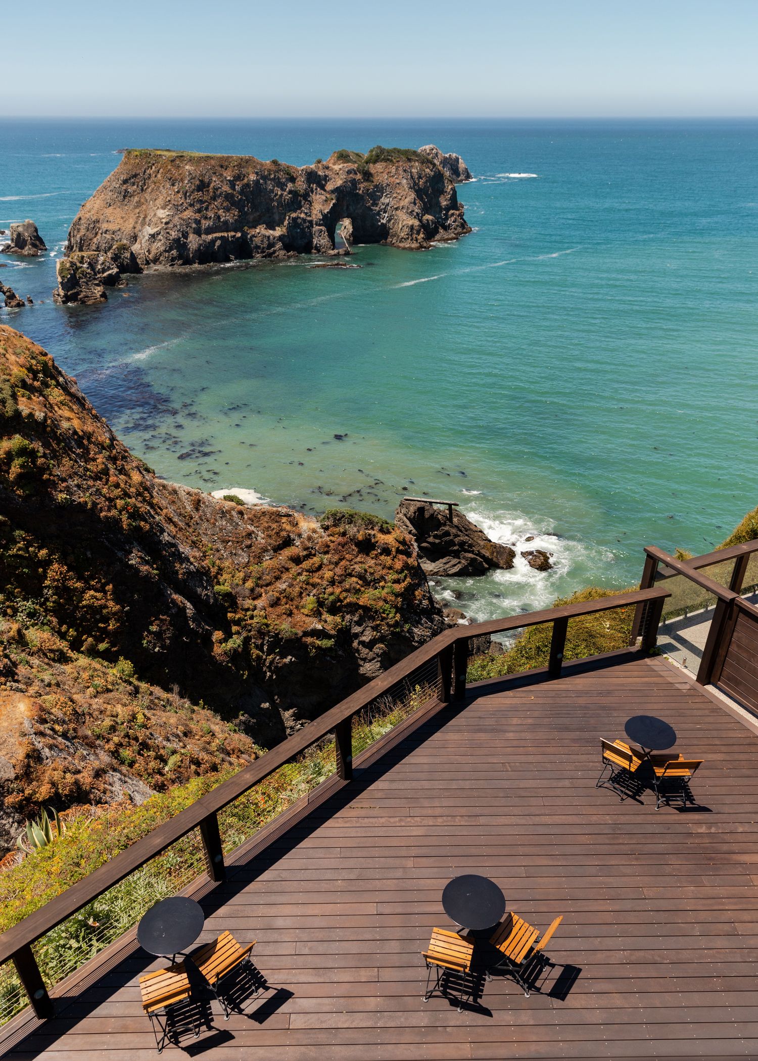 Wooden observation deck overlooking dramatic rocky coastline and turquoise ocean waters.