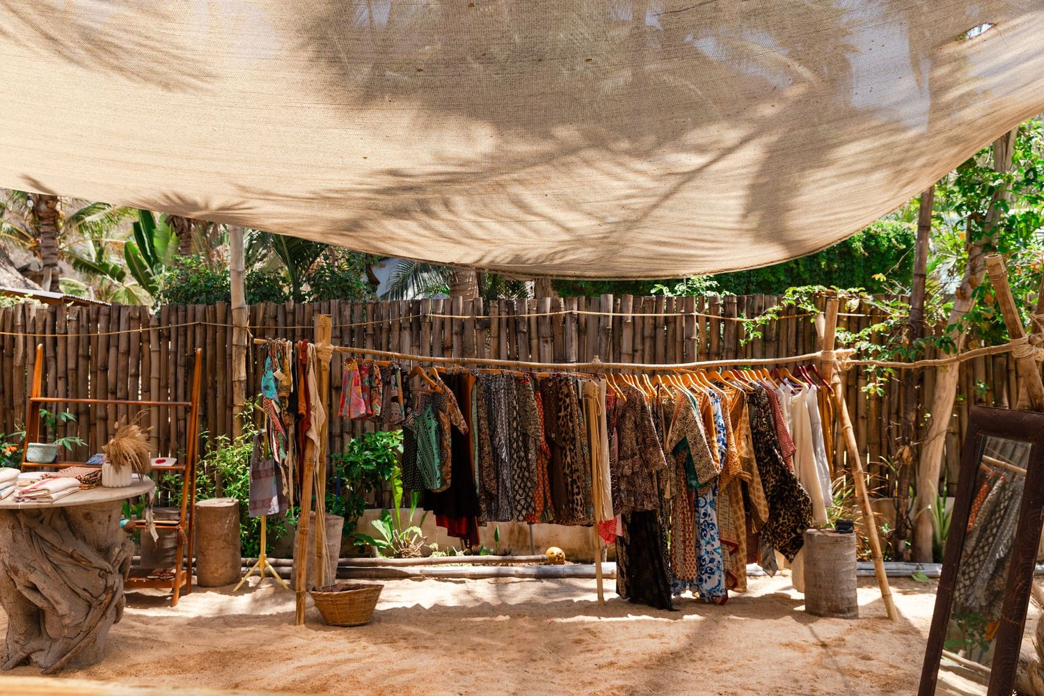 Editorial travel photography of rustic bamboo fencing and canvas shade structures create a natural outdoor space.