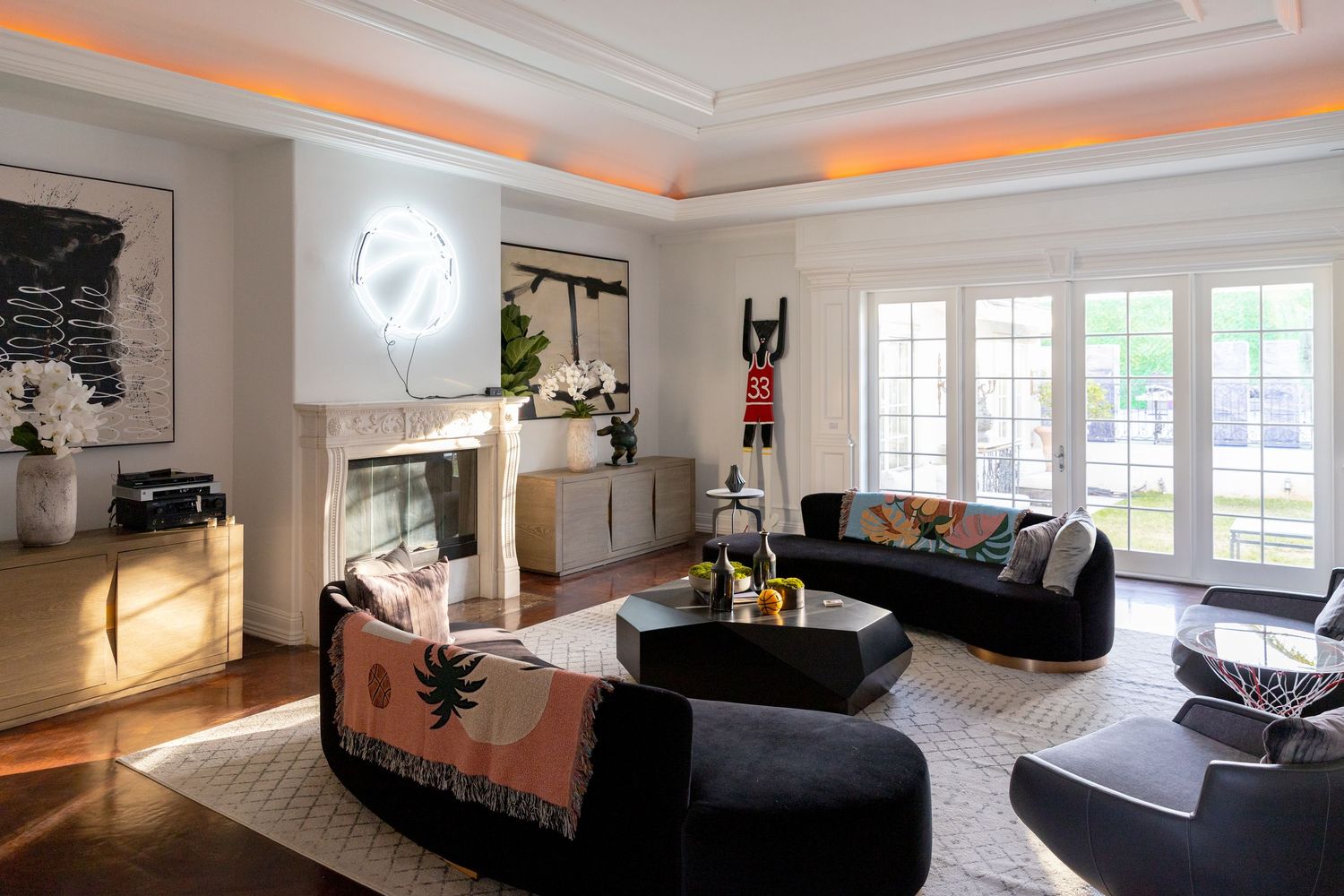 Modern living room interior with orange accent lighting and white crown molding features elegant black furniture.