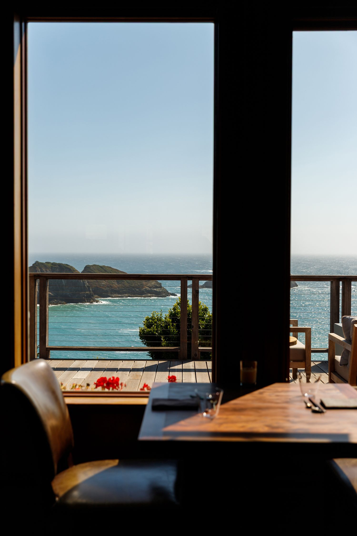 Restaurant table by window overlooking scenic coastal cliffs. Hospitality photographer. Professional restaurant photographer in Colorado.