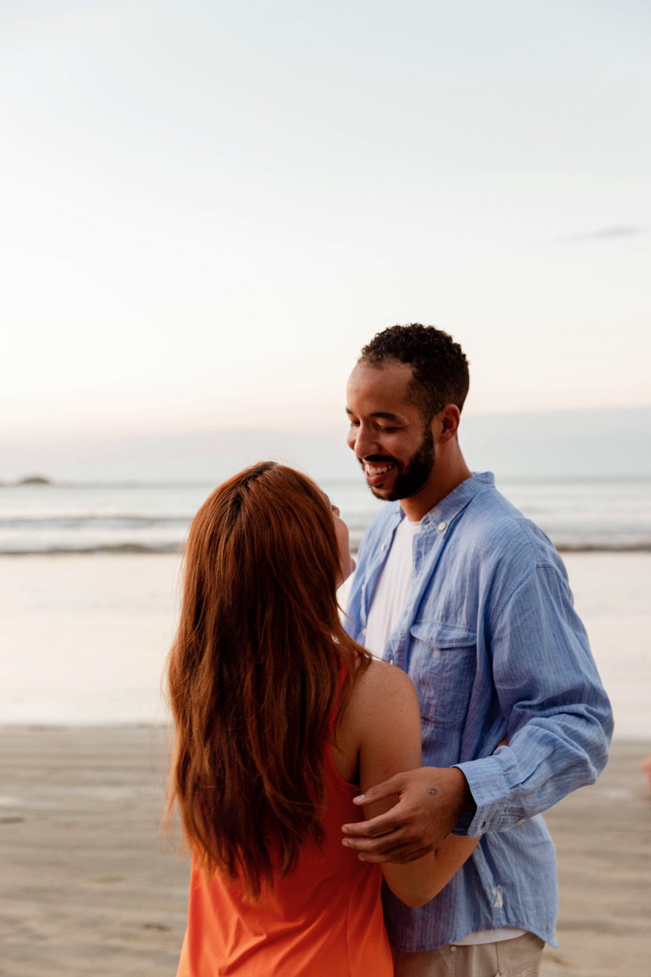 A joyful couple shares a tender moment together on a peaceful beach at sunset.