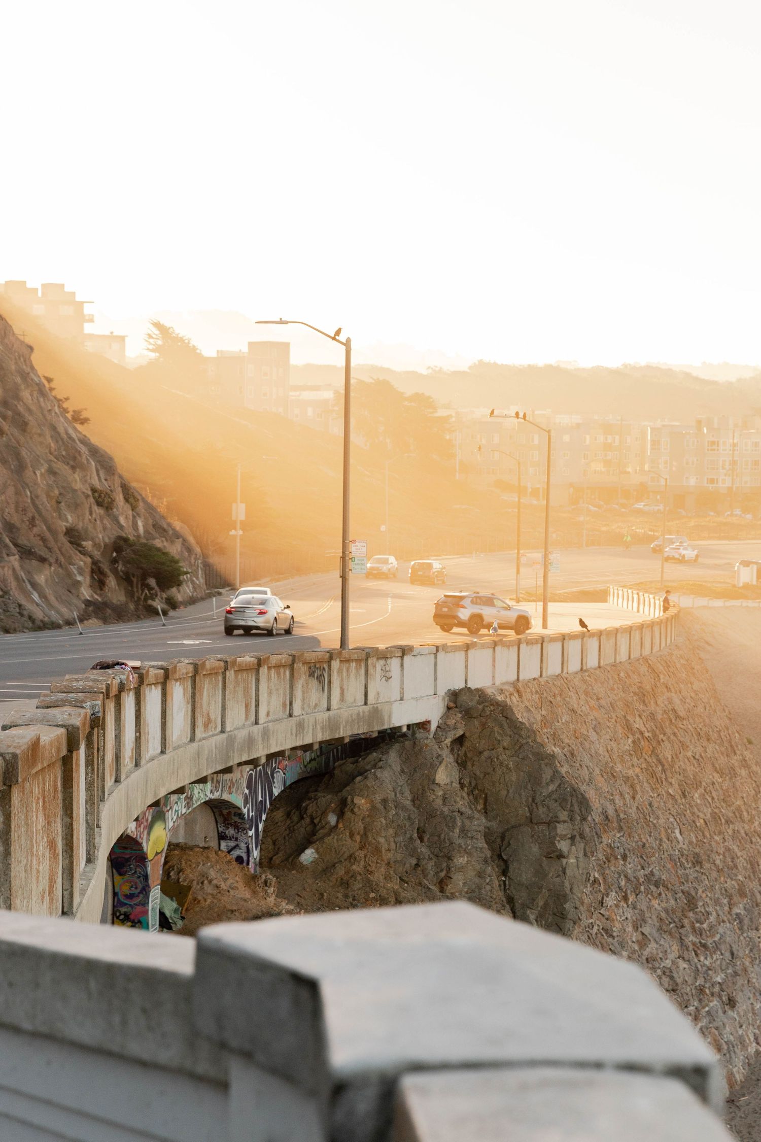 Travel image of the PCH at sunrise with golden light illuminating the rocky cliffs below taken by editorial photographer based in Denver CO.