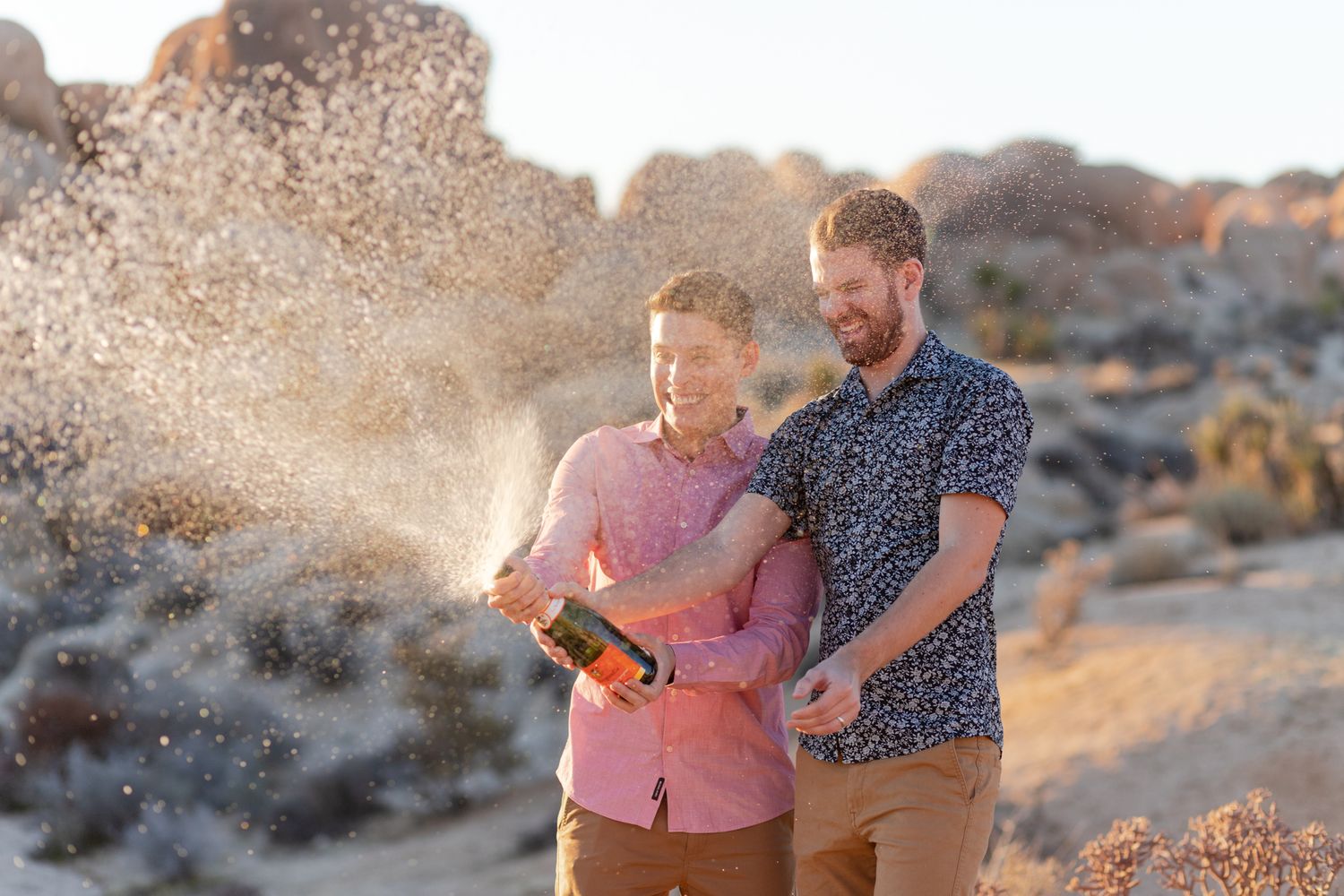 Romantic desert photoshoot with couple among large boulders during golden hour.