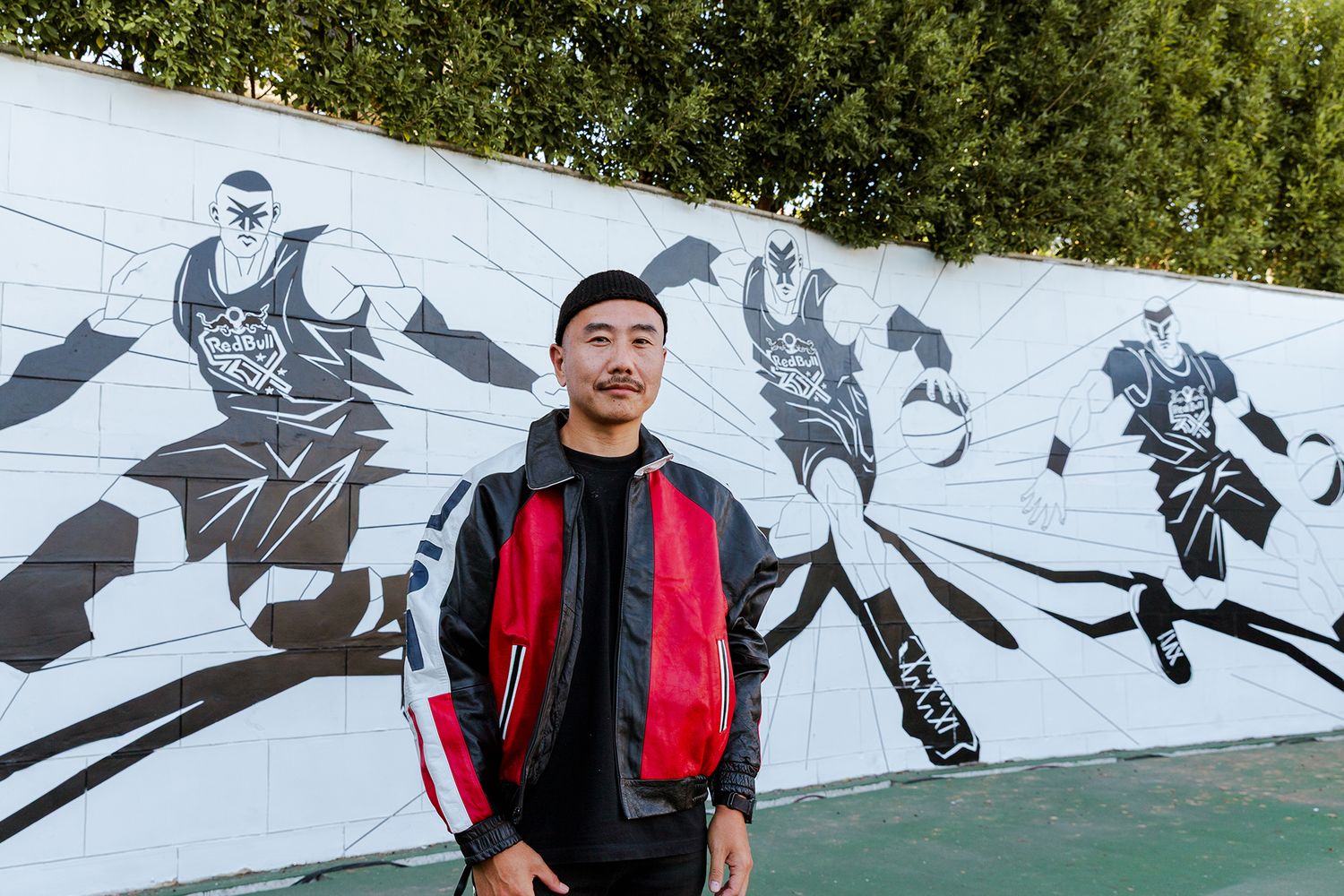 A series of black and white street art murals depicting dynamic athletic figures in motion decorates an outdoor wall.