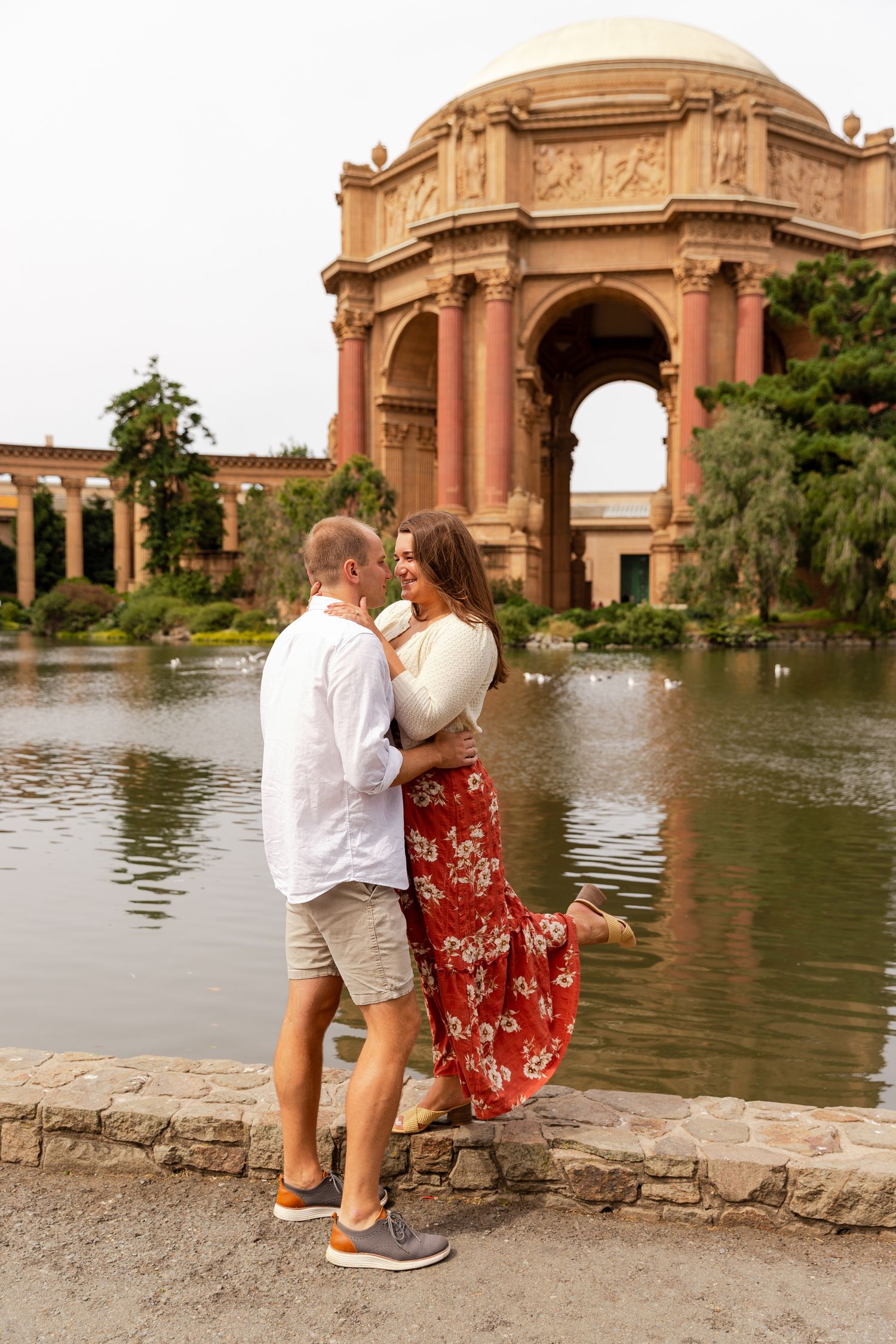 A couple enjoys a romantic moment at the Palace of Fine Arts in San Francisco during sunset.