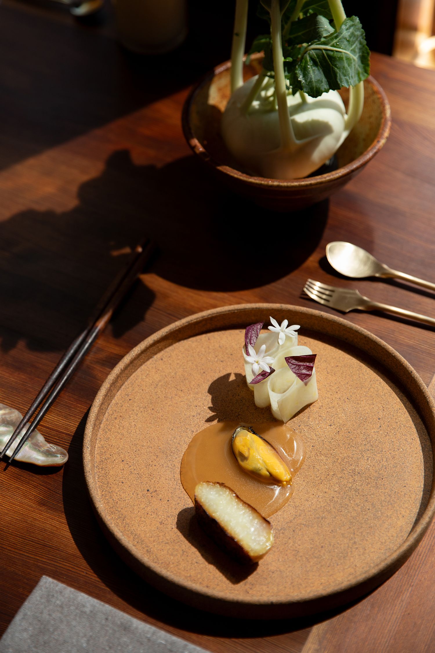 Elegant plated dessert on a textured brown ceramic plate with delicate garnishes. Professional restaurant photographer in Denver, Colorado.