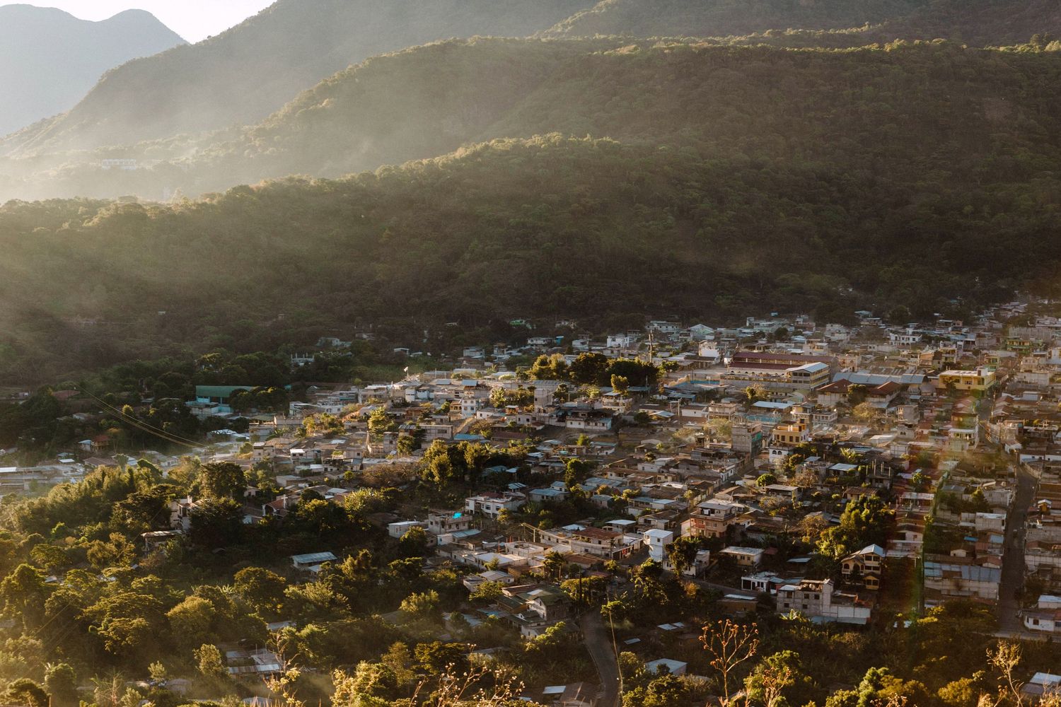 Editorial travel photography of hillside town nestled in mountains at sunset with densely packed buildings catching golden light.