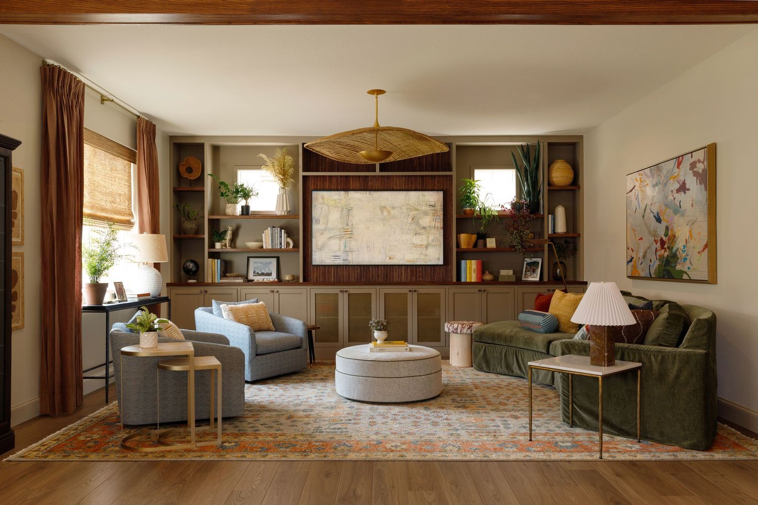 Cozy living room with green sofa, gray chairs, built-in bookshelves, wooden canoe ceiling decor, and warm earth-tone rug.