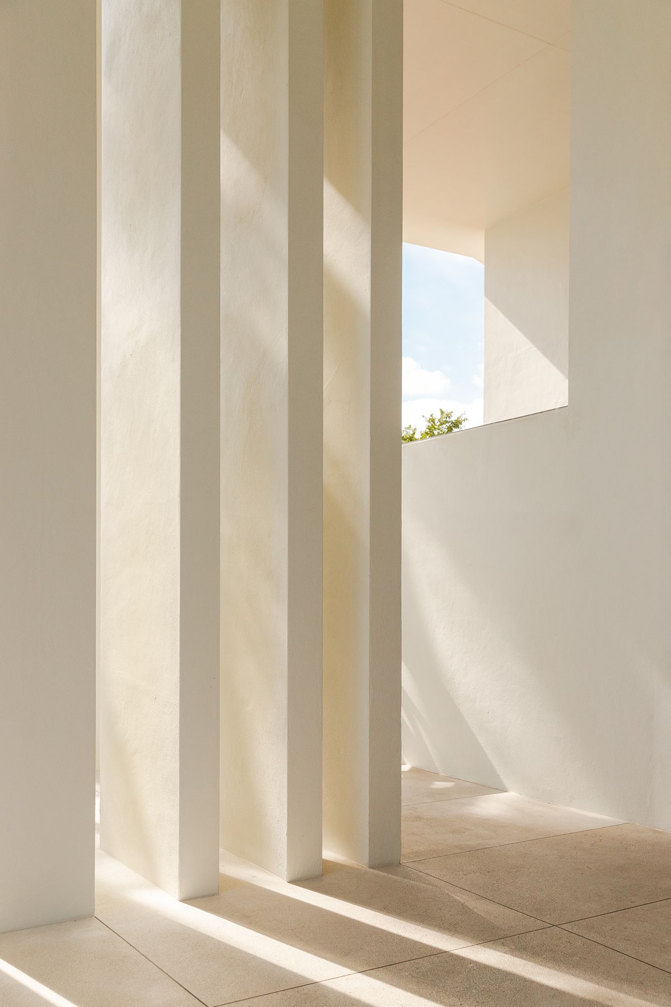 Modern white architectural photograph where the dramatic shadows cast geometric patterns on the floor. Moody interior photography.